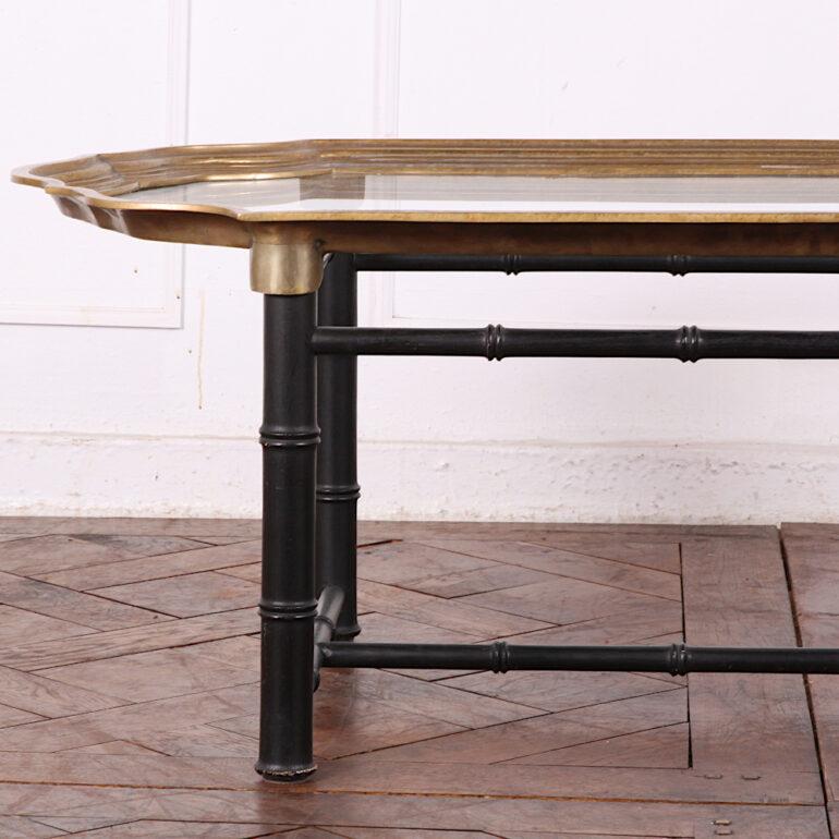 A mid-20th century coffee table featuring a heavy shaped brass-edged top with glass surface and a simple turned bamboo base. Made in France from 1970s, attributed to Maison Jansen.