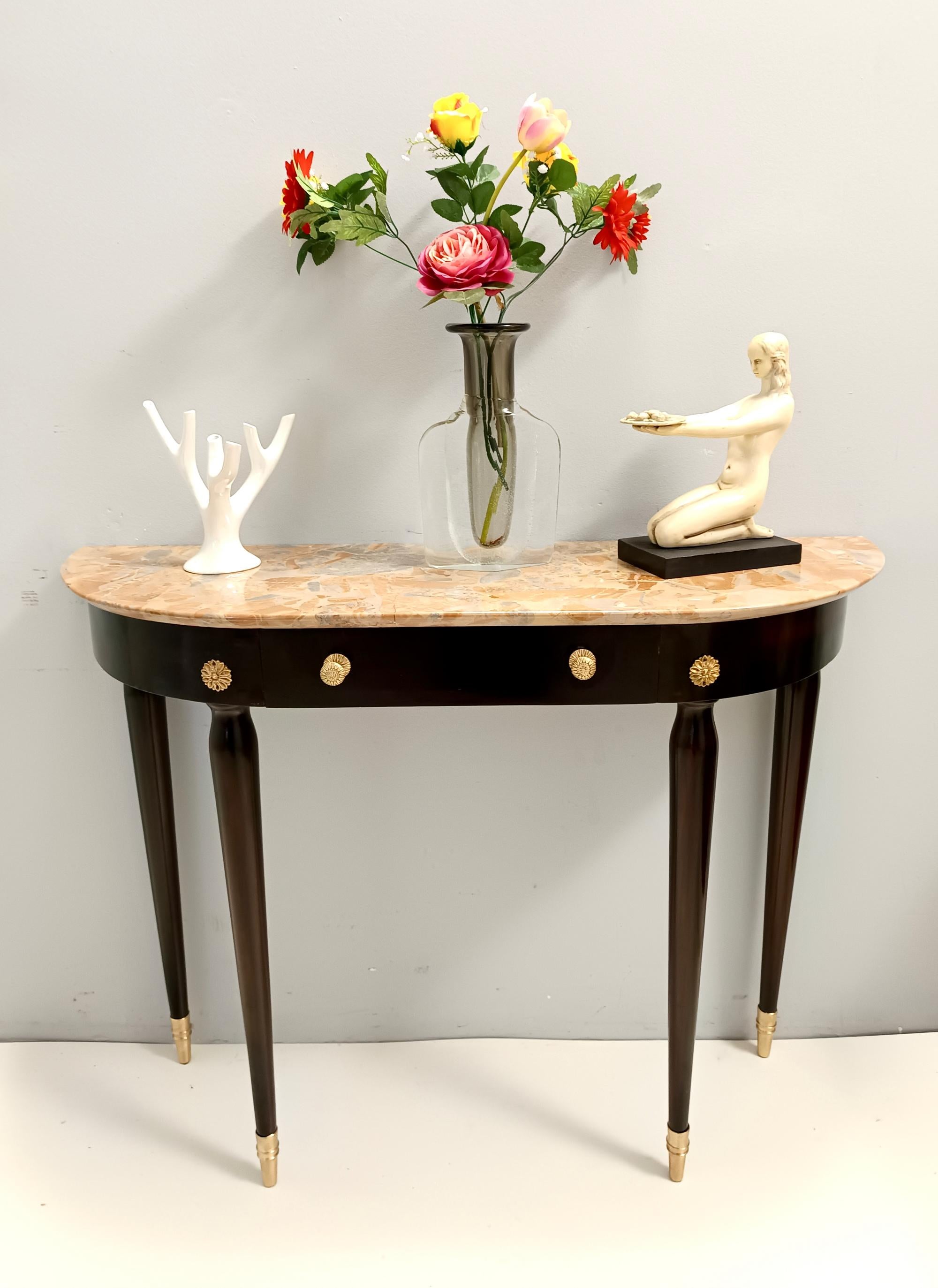Made in Italy, 1940s - 1950s.
It features an ebonized beech frame with brass feet caps and details and a demilune Macchiavecchia marble top.
This console may show slight traces of use since it's vintage, but the frame has been recently polished by