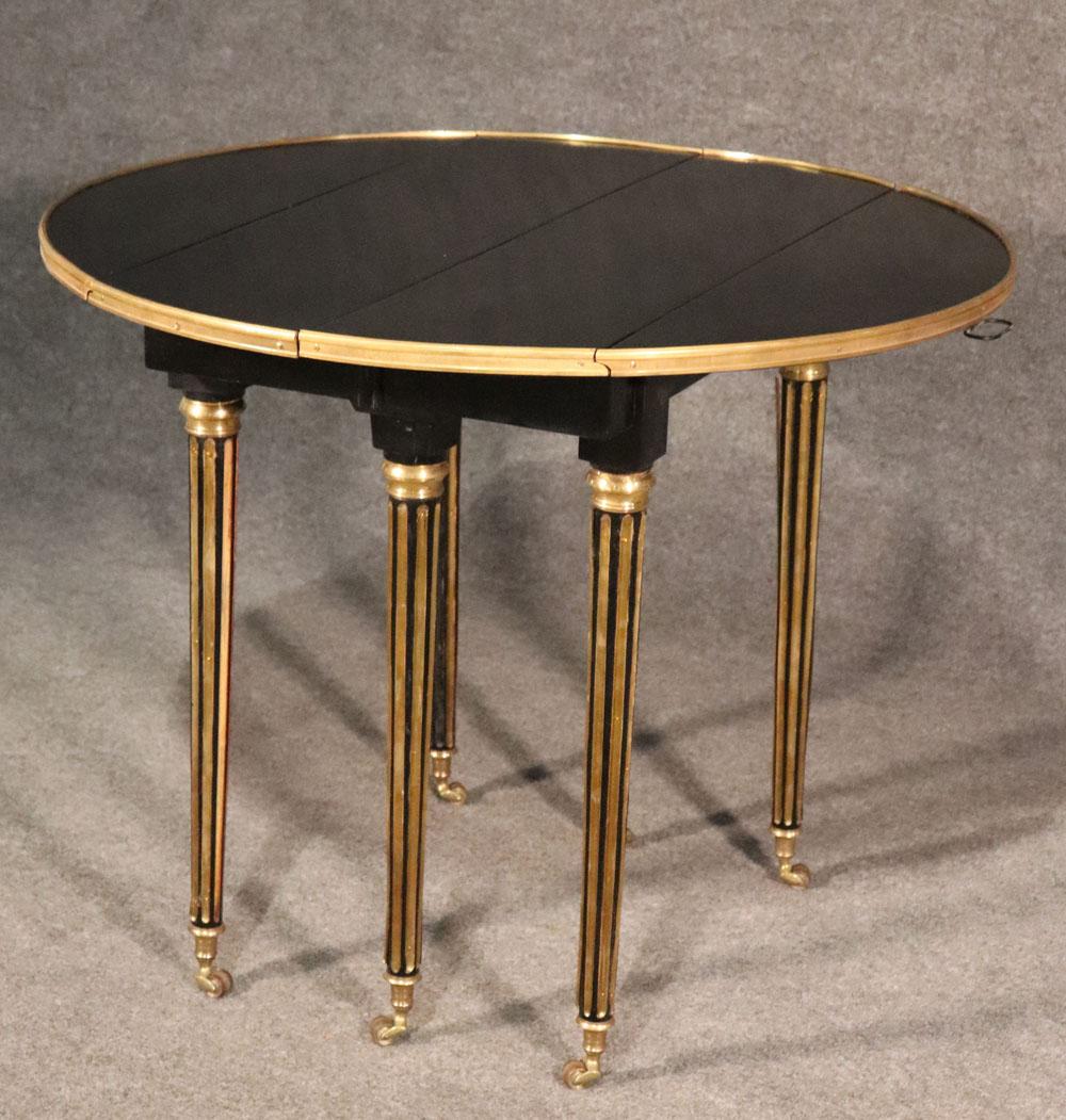 This is a very rare size as far as Maison Jansen dining tables go. The size measures 37 wide x 37 deep and is 29.5 tall and has 3 18 inch leaves. The table is adorned in brass trim with inlaid brass fluted Louis XVI style legs and casters. This is a