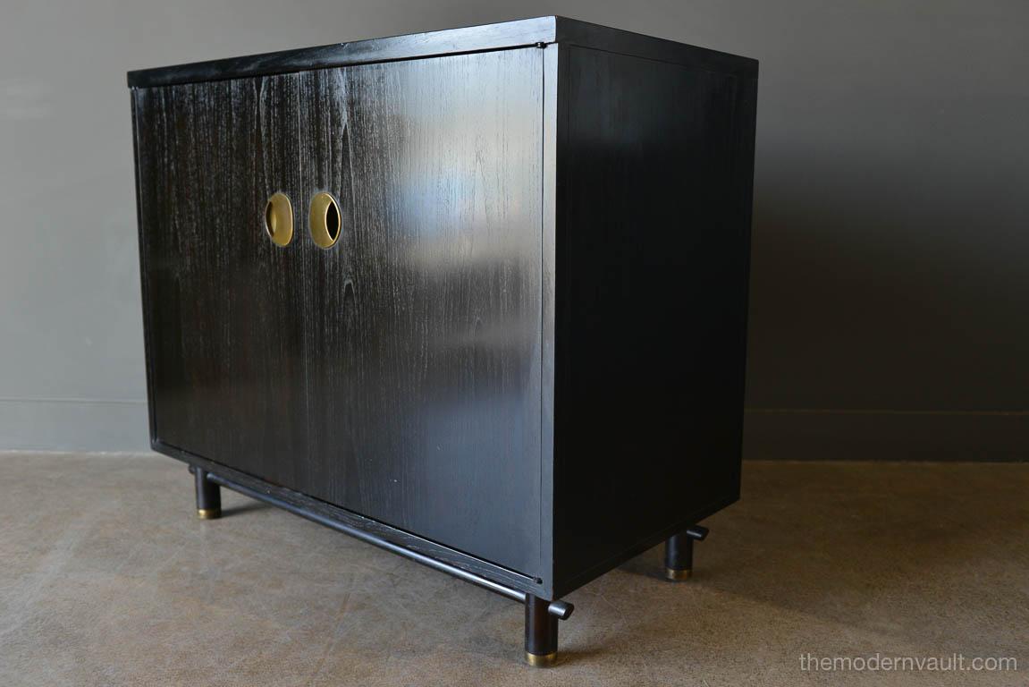 Ebonized cabinet with brass hardware by Baker, circa 1970. Brass hardware on door and legs. Two inner drawers with a sliding interior drawer that is adjustable and/or removable. Finished on the reverse. Good vintage condition with only slight wear