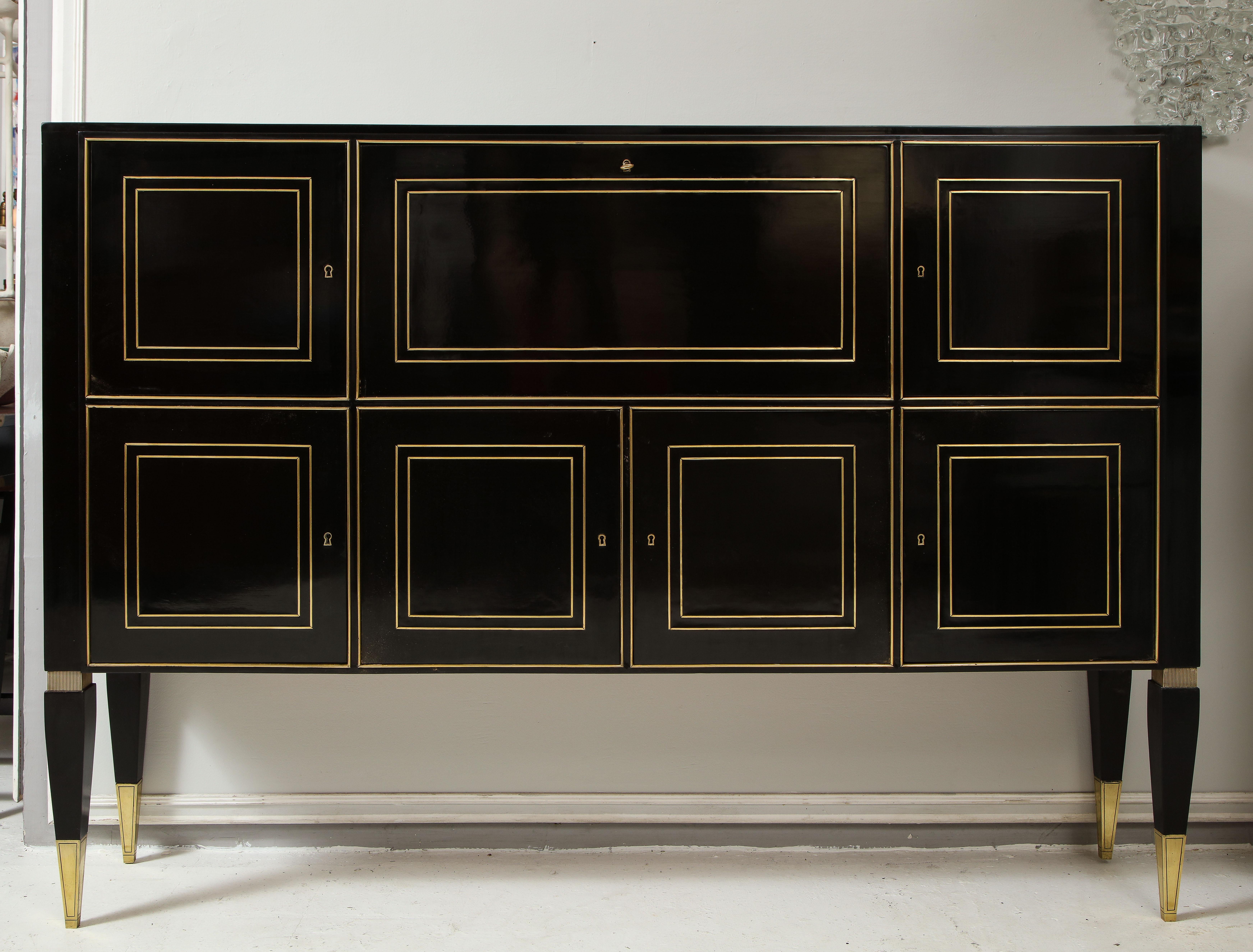 Ebonized cabinet with brass-inlays on tapered legs
- featuring 7 doors- central drawer containing drawers and a writing surface.