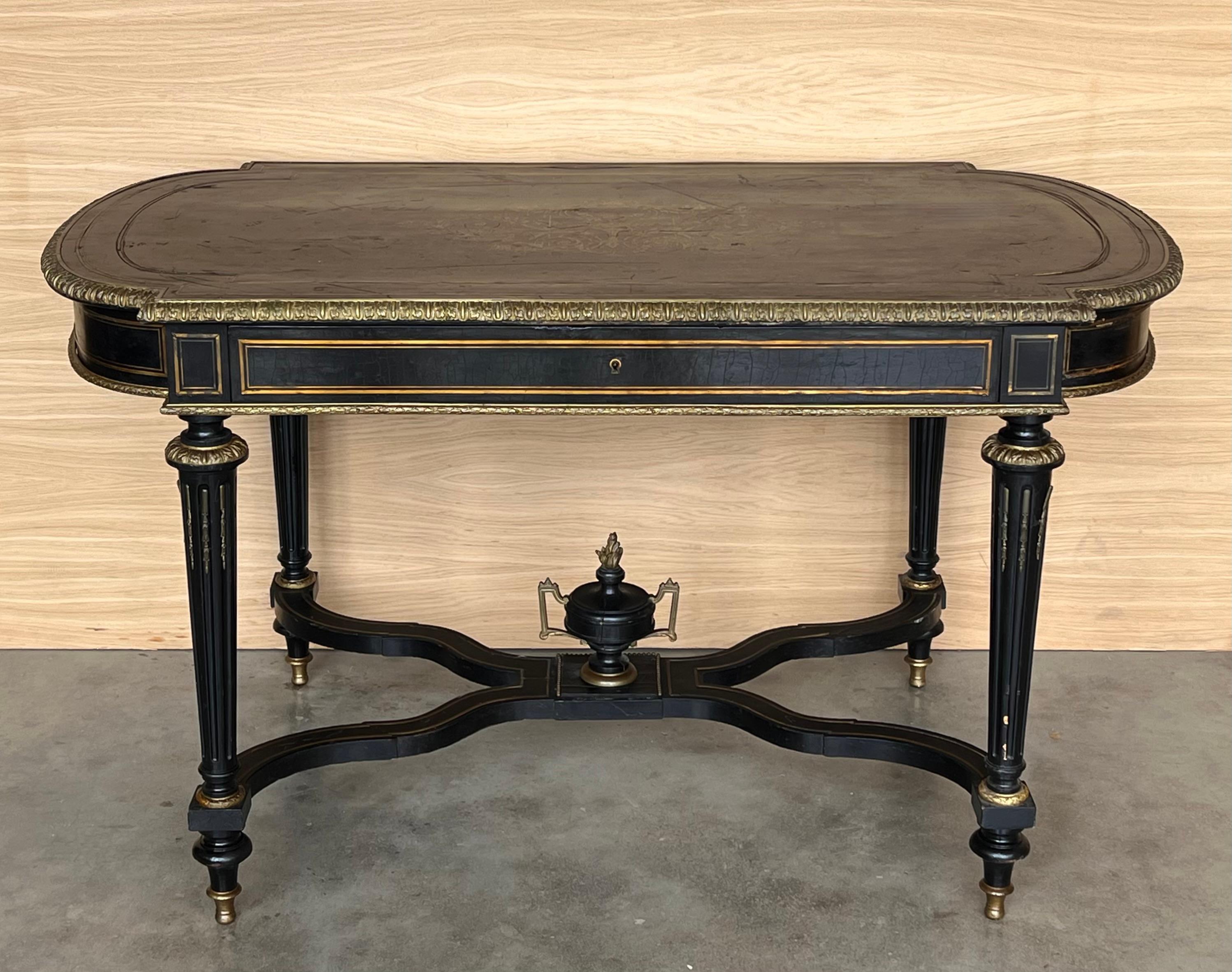 An imposing Napoleon III center table (or 'Table de Milieu') in ebonized fruit wood, rectangular in shape, with rounded sides.  Its ornate top, which is bordered all around with a gilt bronze frieze and two further inner bands, features at its