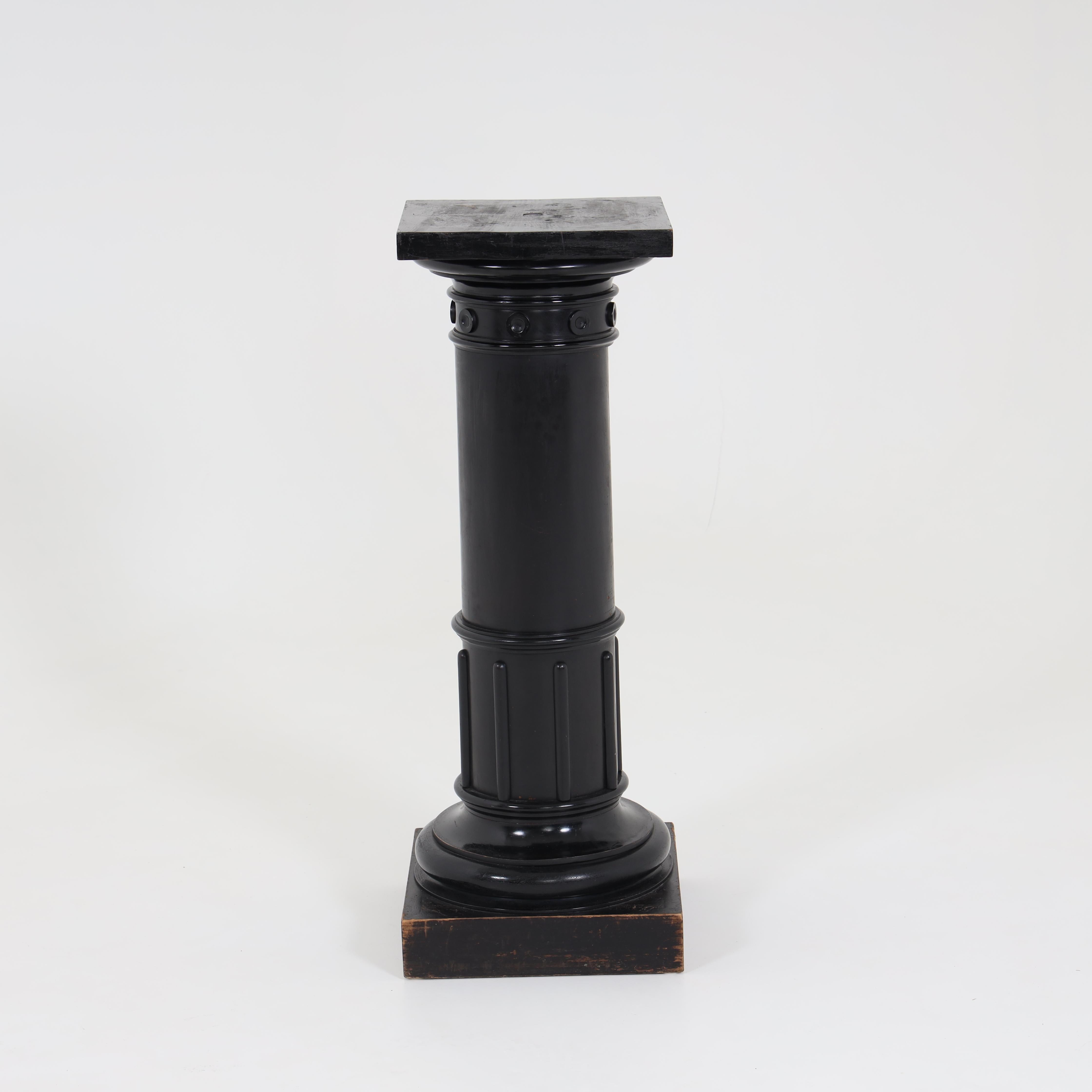 Ebonized wooden column on square plinth and profiled base and capital.