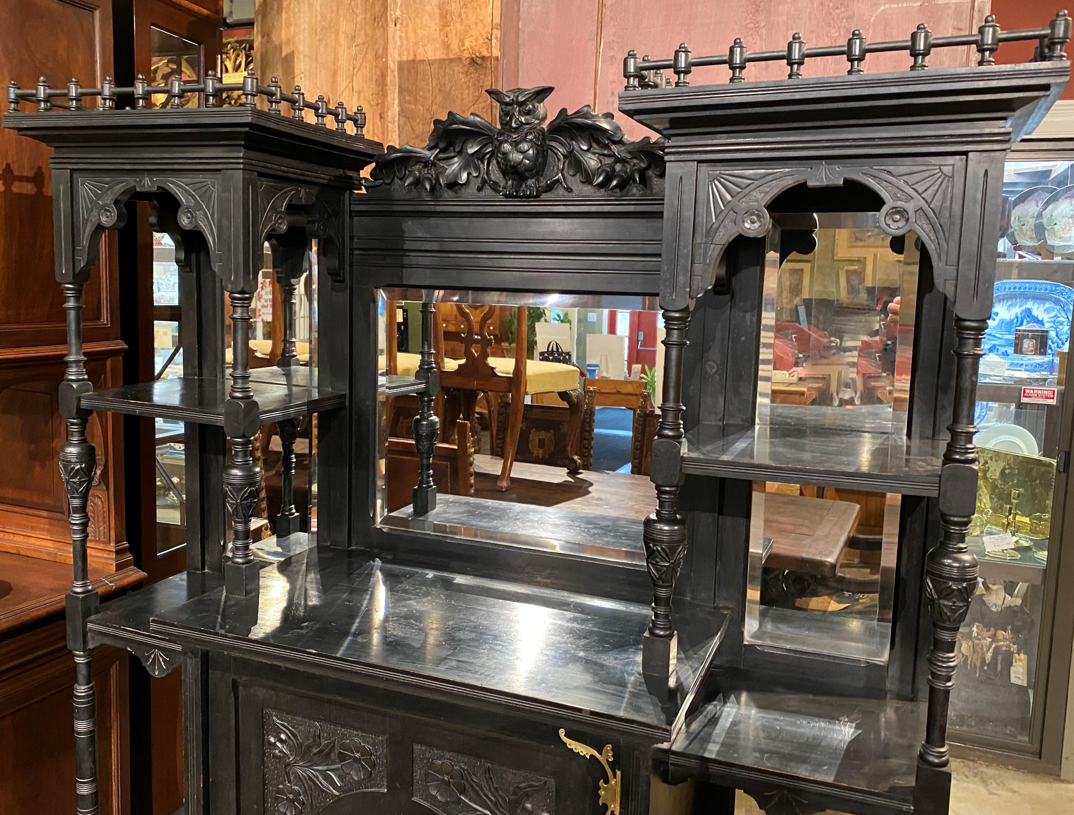 A fine Aesthetic period ebonized étagère cabinet attributed to Bancroft & Dyer of Boston, MA, with carved owl crest, a central cabinet with single foliate carved door and original brass hardware, opening to a single shelf storage compartment, over