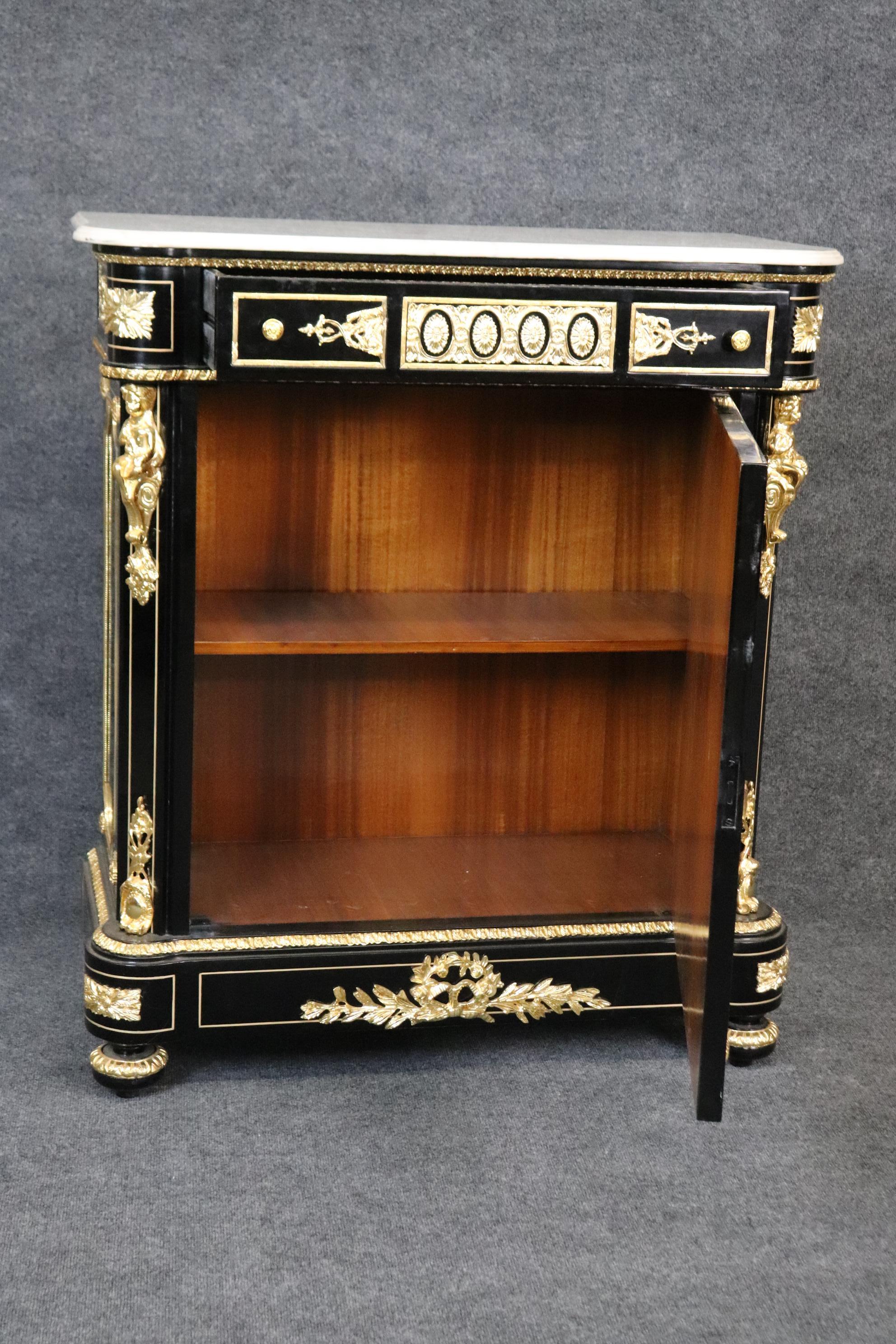 This is a gorgeous black lacquered or ebonized side cabinet in the Napoleonic style. The cabinet features beautiful bright brass castings of cherubs and figures and various other forms of ormolu. The cabinet Measures 44.5 tall x 38.75 wide x 17.5