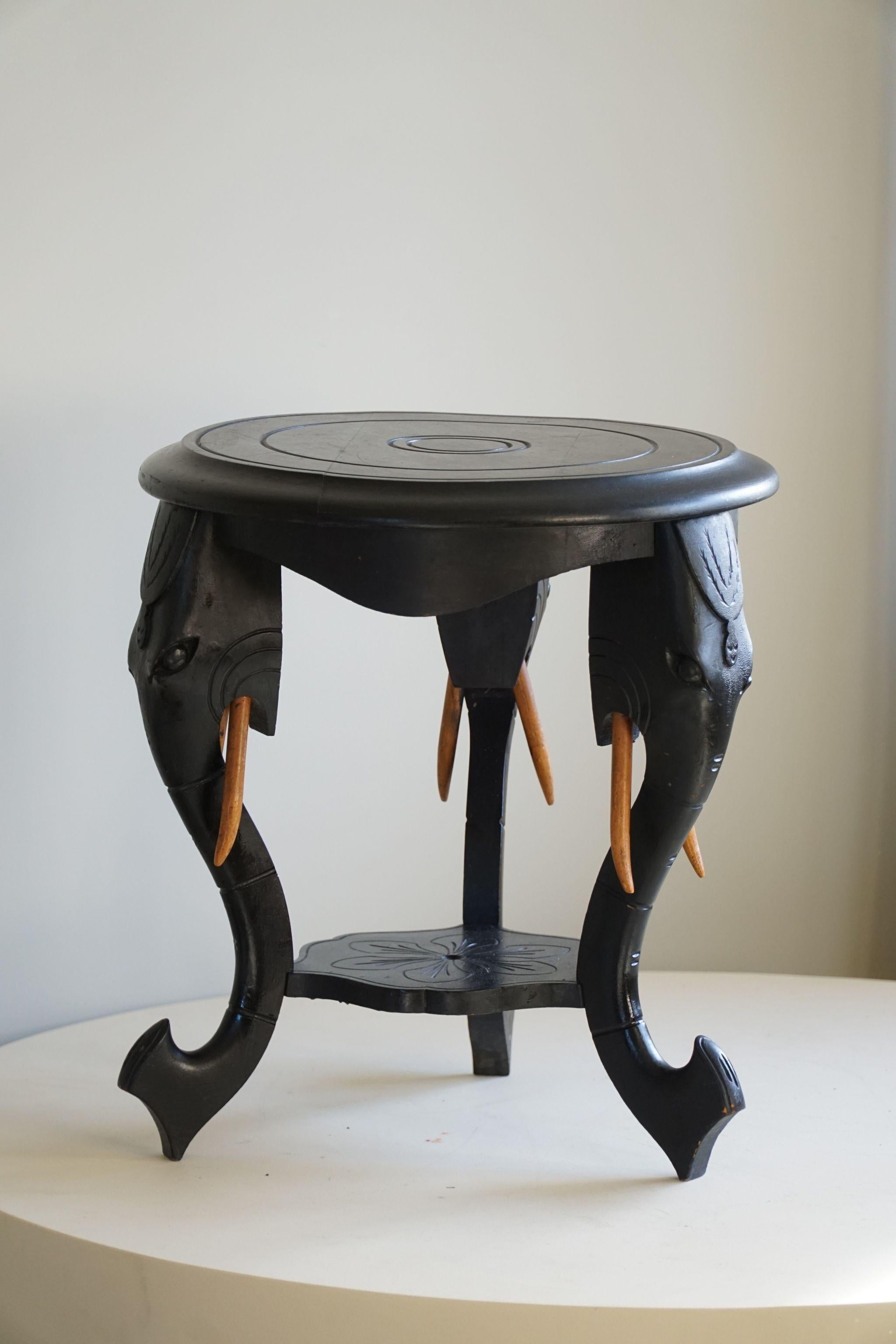 Sculpté Table d'appoint en bois dur ébénisé avec 3 pieds à tête d'éléphant, Inde orientale, années 1920 en vente