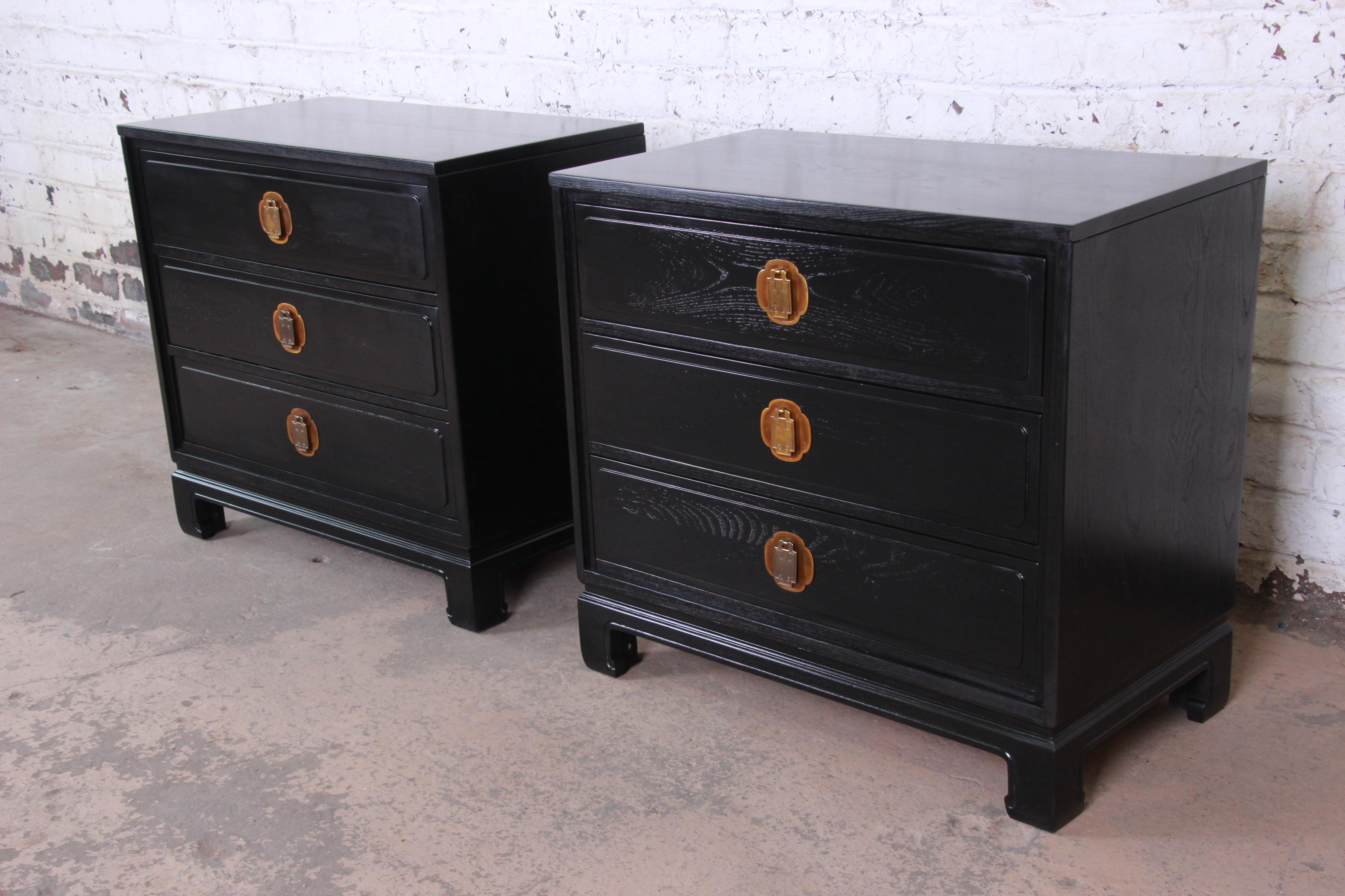 A gorgeous pair of newly ebonized Hollywood Regency chinoiserie large bedside tables or bachelor chests by Davis Cabinet Co. The chests feature a stunning ebonized finish over walnut and sleek Mid-Century Modern design with an Asian flair. They