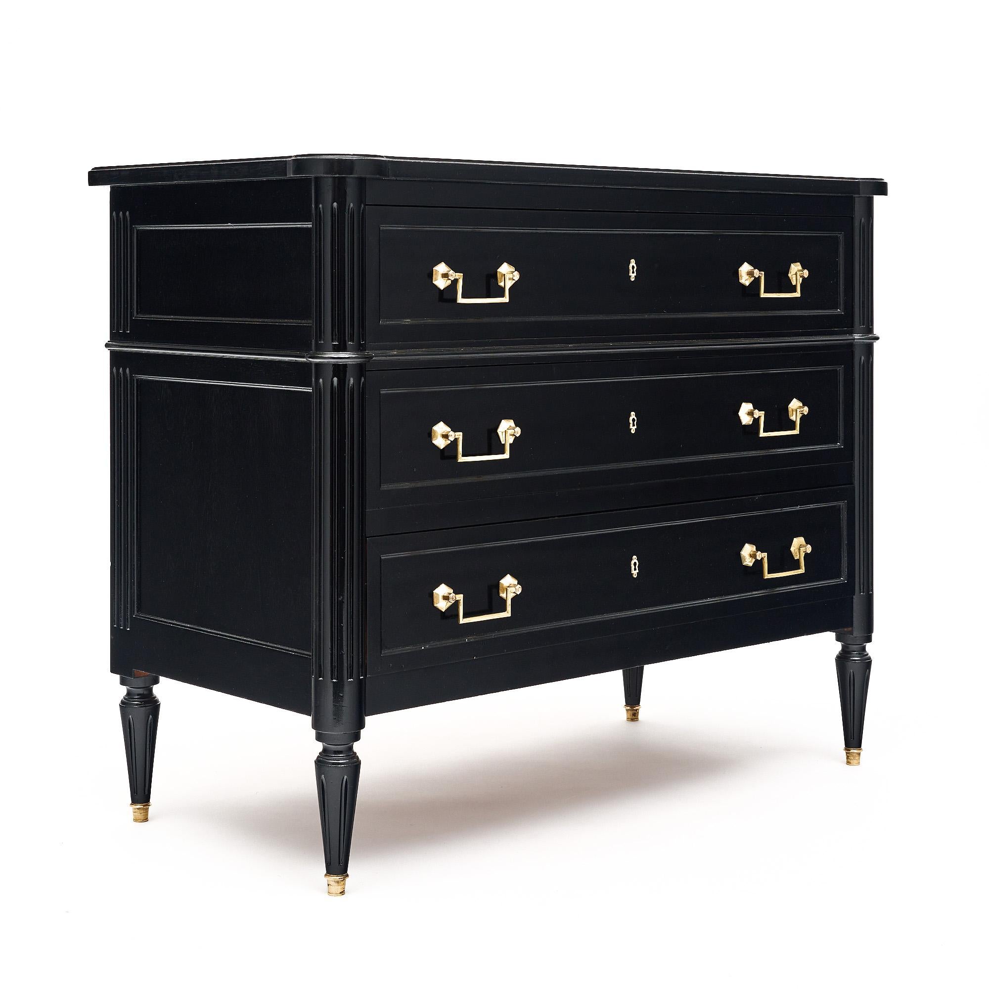 Petite chest of drawers from France in the Louis XVI style. This piece is made of mahogany that has been ebonized and finished with a lustrous French polish. All three dovetailed drawers boast finely cast brass pulls. The chest sits on four tapered,