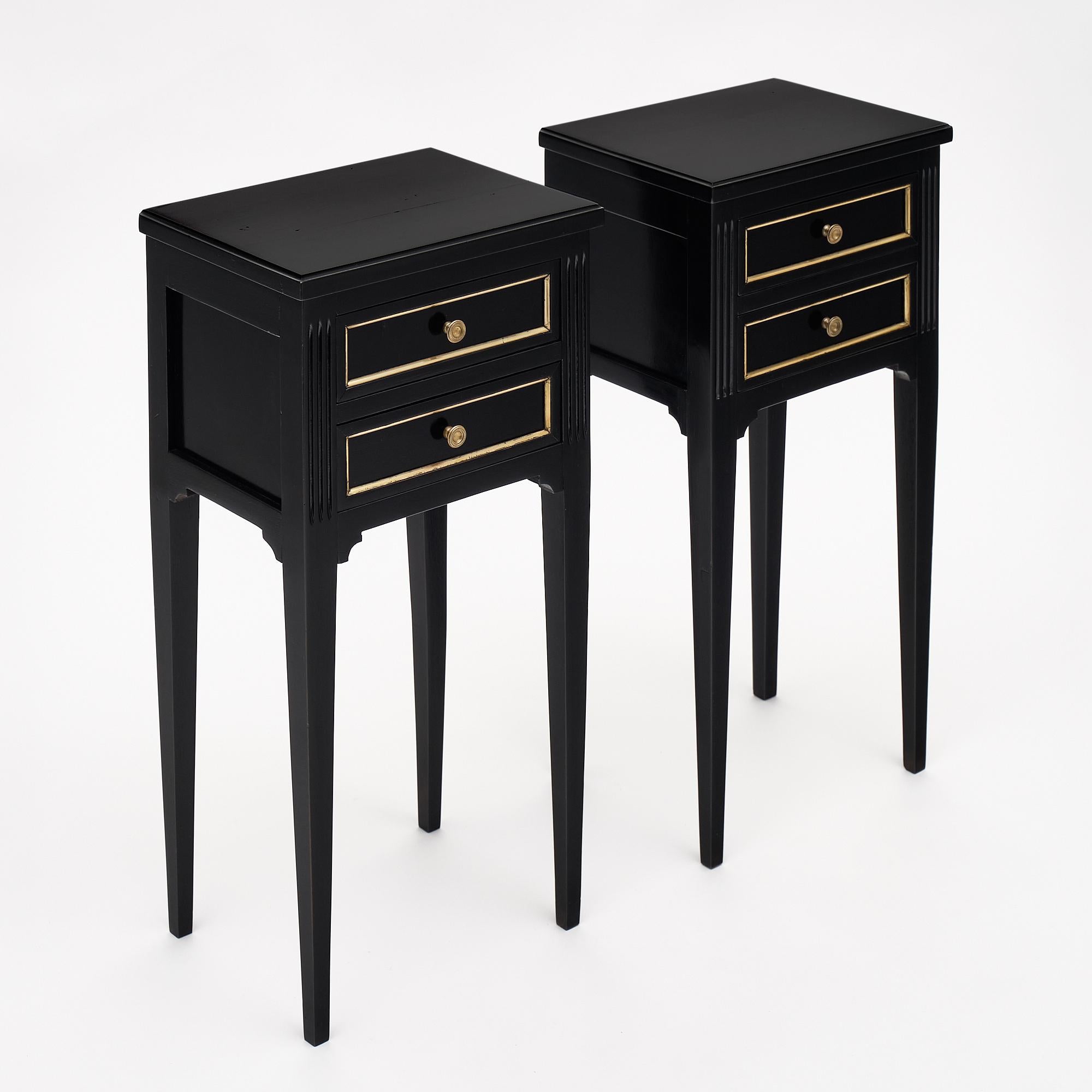 Pair of ebonized Louis XVI style side tables from France. We love the antique style and long tapered legs. They are made of solid mahogany that has been finished in a lustrous French polish. Each has two dovetailed drawers; trimmed with brass.