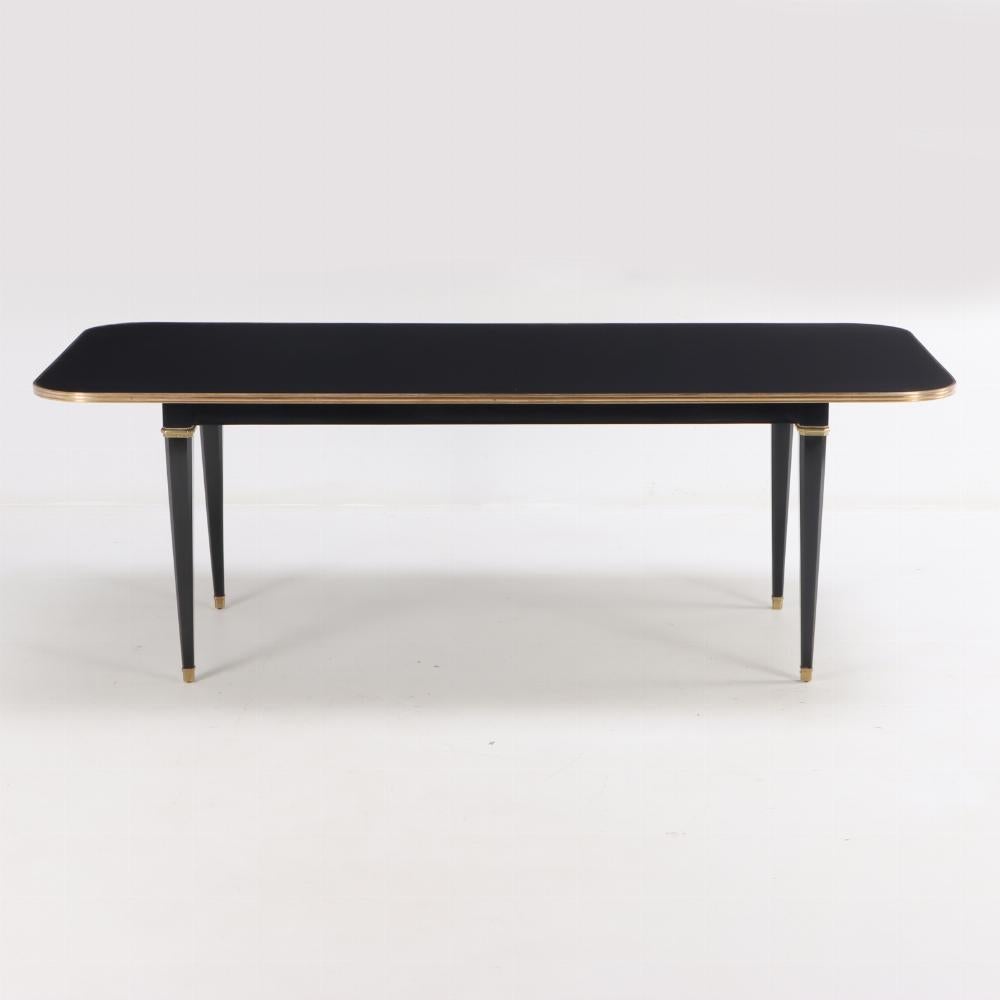 An elegant ebonized mahogany and bronze mounted dining table attributed to Jansen,  C 1940. This table has great proportions with a rounded corner top and beautiful bronze mounts to accentuate the square tapering legs. This table does not accept