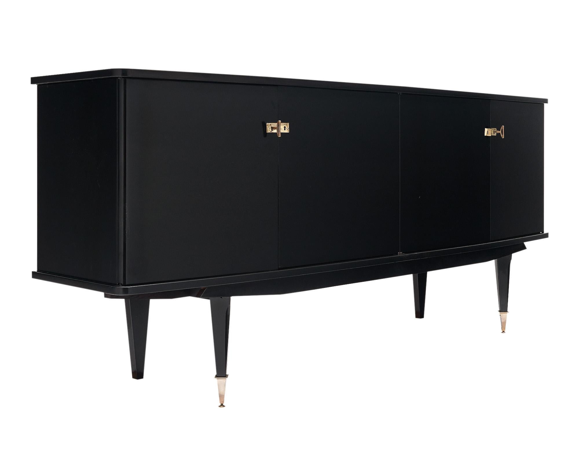 Buffet from France in the mid-century style. This enfilade has been ebonized and finished with a lustrous French polish. There are four doors that open to a lemonwood interior shelving and 2 glass shelves. It is supported by four tapered legs with