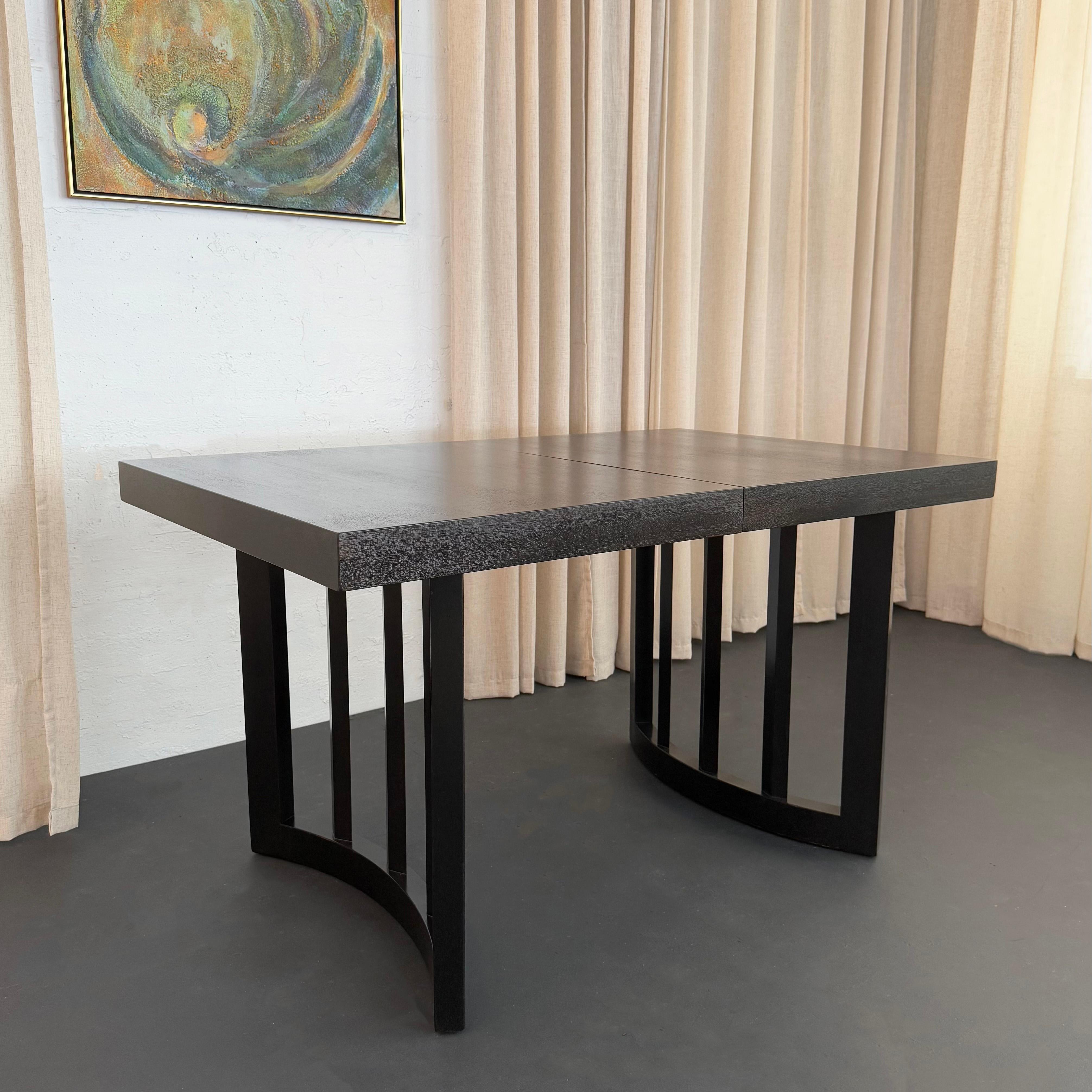 This Mid-Century Modern ebonized oak extension dining table was designed by the Hungarian born architect and interior designer Paul Laszlo, manufactured by Brown Saltman circa 1950. This architectural dining table features a ebonized finished to