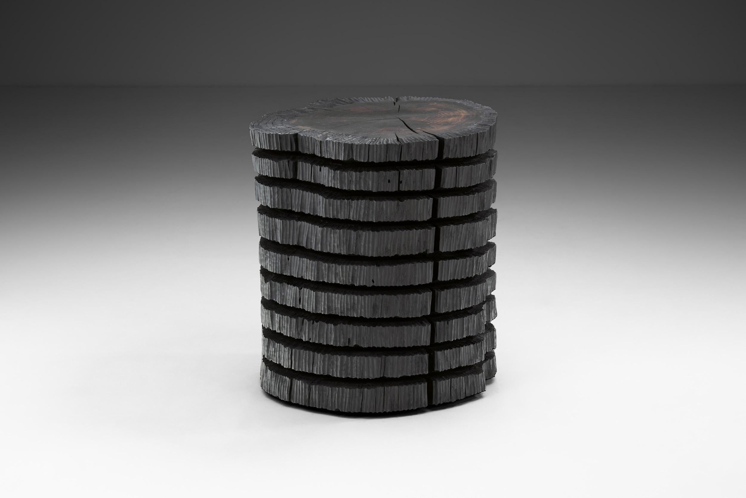 Cette table d'appoint noire est sculptée à la main avec des outils manuels et fabriquée en chêne recyclé avec une finition à l'huile. L'objectif de cet objet est d'explorer la manipulation du bois sans perdre la vérité du matériau et de conserver