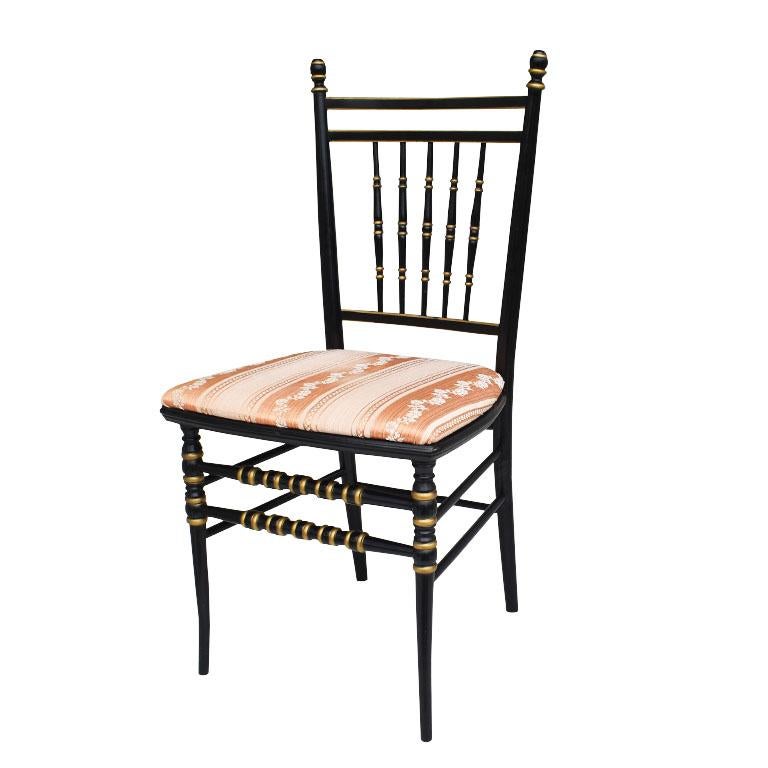 A fabulous ebonized black and gold side chair or ballroom chair. Upholstered in a peach and cream floral striped fabric, this petite chair will be great as a side chair, at a dining table, vanity, or in a great room. The spindle back is accented