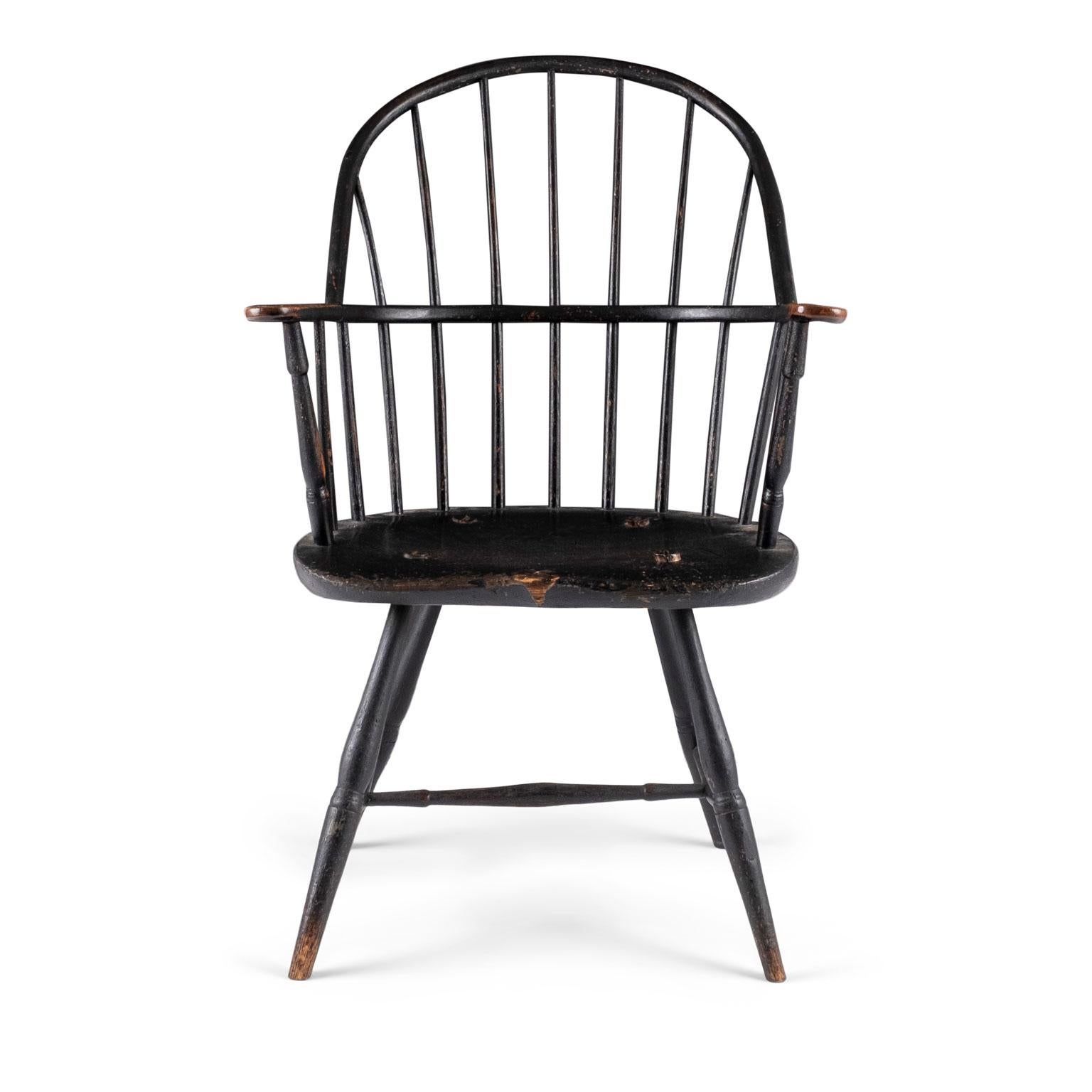 Ebonized sack back Windsor armchair constructed in ash and pine circa 1790-1810 in Rhode Island. Remnants of original (or early) black paint are naturally worn away from two centuries of use to reveal a rich brown wood patina.