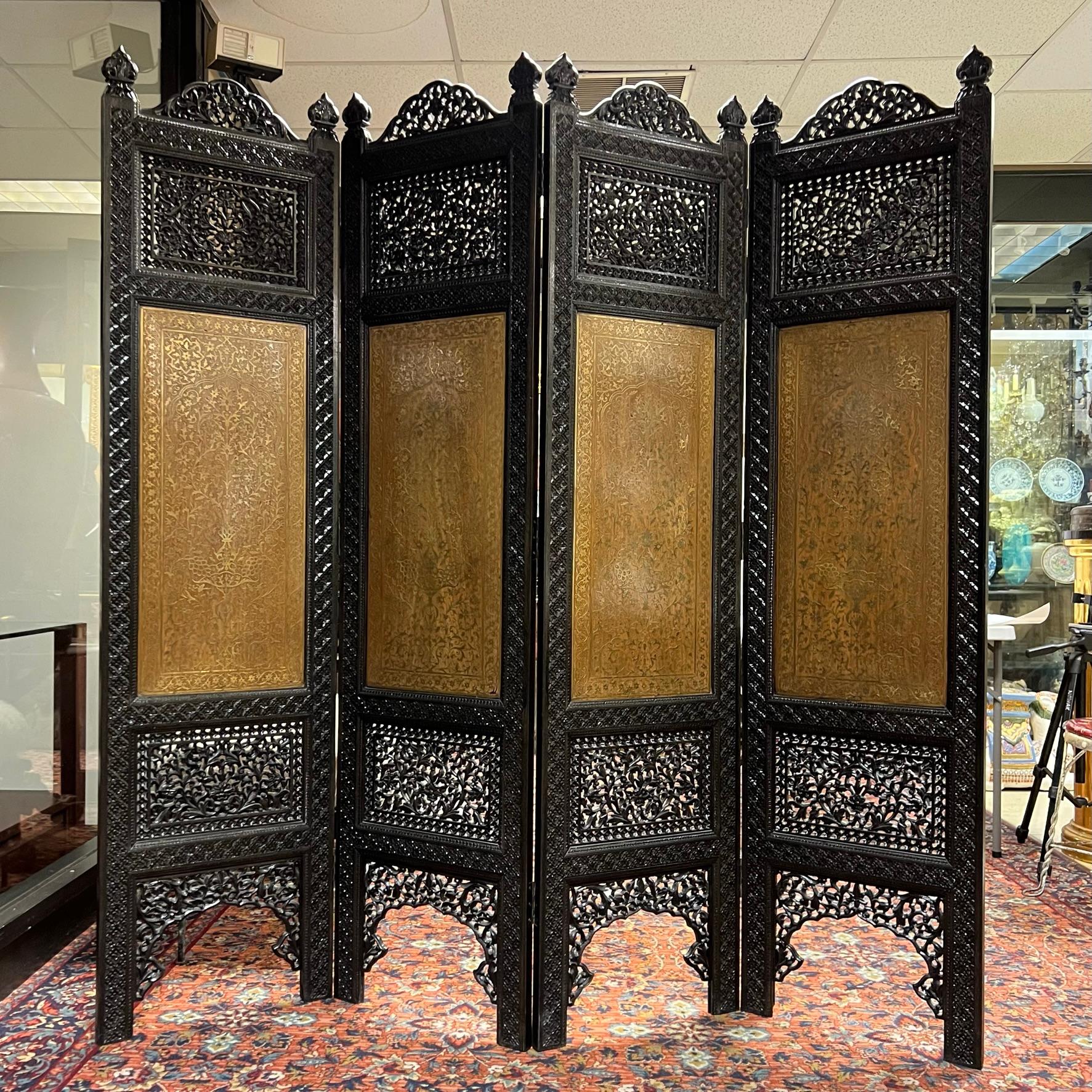 Exceptional room divider with finely carved floral openwork, inlaid brass depicting floral arabesque designs, fleur-de-lis finials and painted black finish.  Four panels each measuring 18 3/4 inches wide and 75 1/2 inches tall.