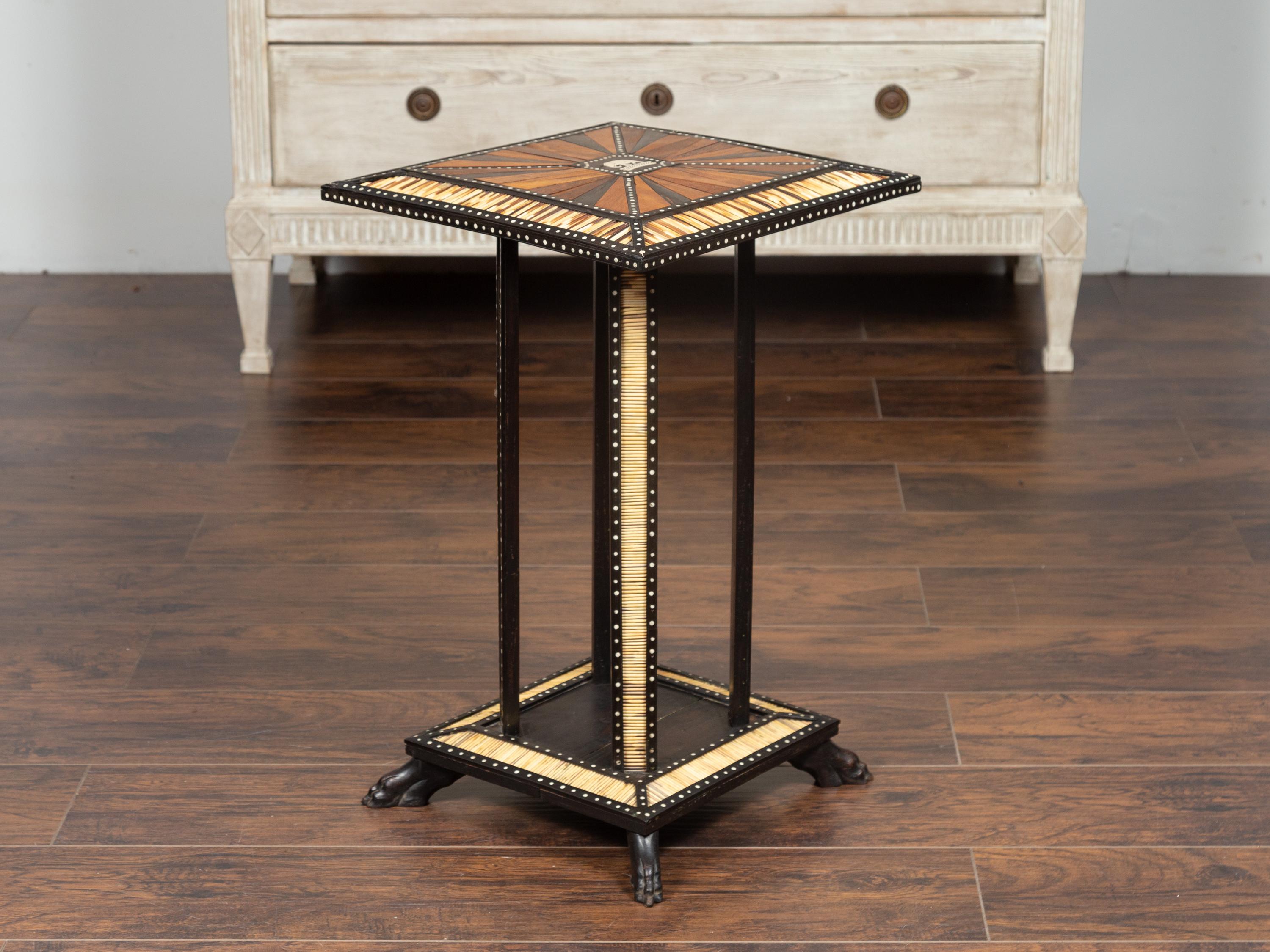 An Anglo Indian ebonized side table from the early 20th century, with porcupine quill inlay and elephant motif. Born at the Turn of the Century, this exquisite and table features a square top with beveled edges, beautifully adorned with a central