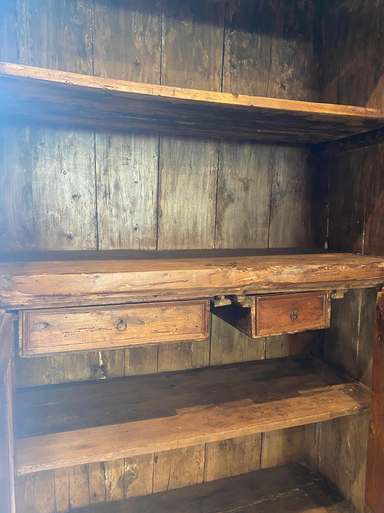 19th century ebonized two-door pine cabinet.  Interior has two lower doors concealing two drawers with exposed upper fixed shelves.  Exterior doors have locks with keys.  Original painted surface has worn through areas on surface while the interior