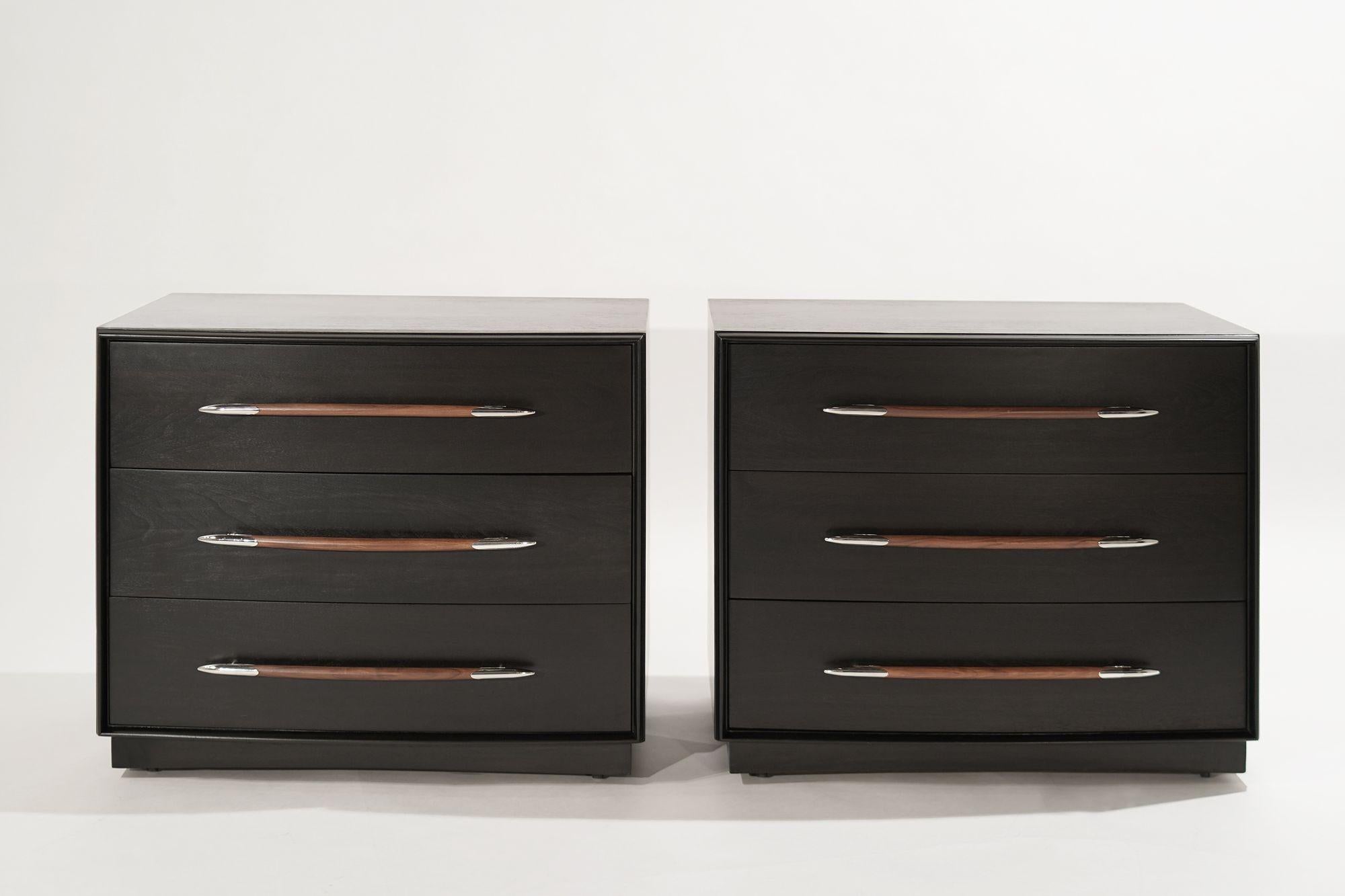 Rare set of matching bedside tables or chests of drawers designed by T.H. Robsjohn-Gibbings for Widdicomb, circa 1950-1959. Completely restored walnut cases done in ebony, contrasting walnut handles highlighted by spear-tip nickel hardware.
