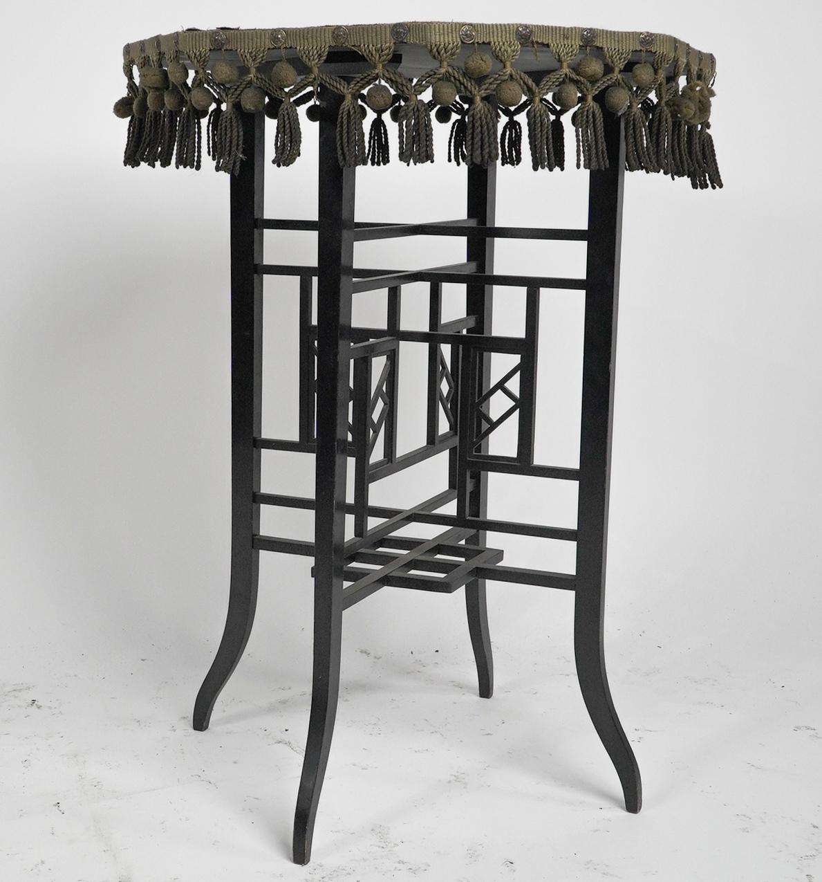 An Anglo-Japanese ebonized walnut side table retaining the original faded green baize top and all its little matching hanging balls. The legs have a multitude of fretwork details uniting the four legs into a flourishing Japanese design.