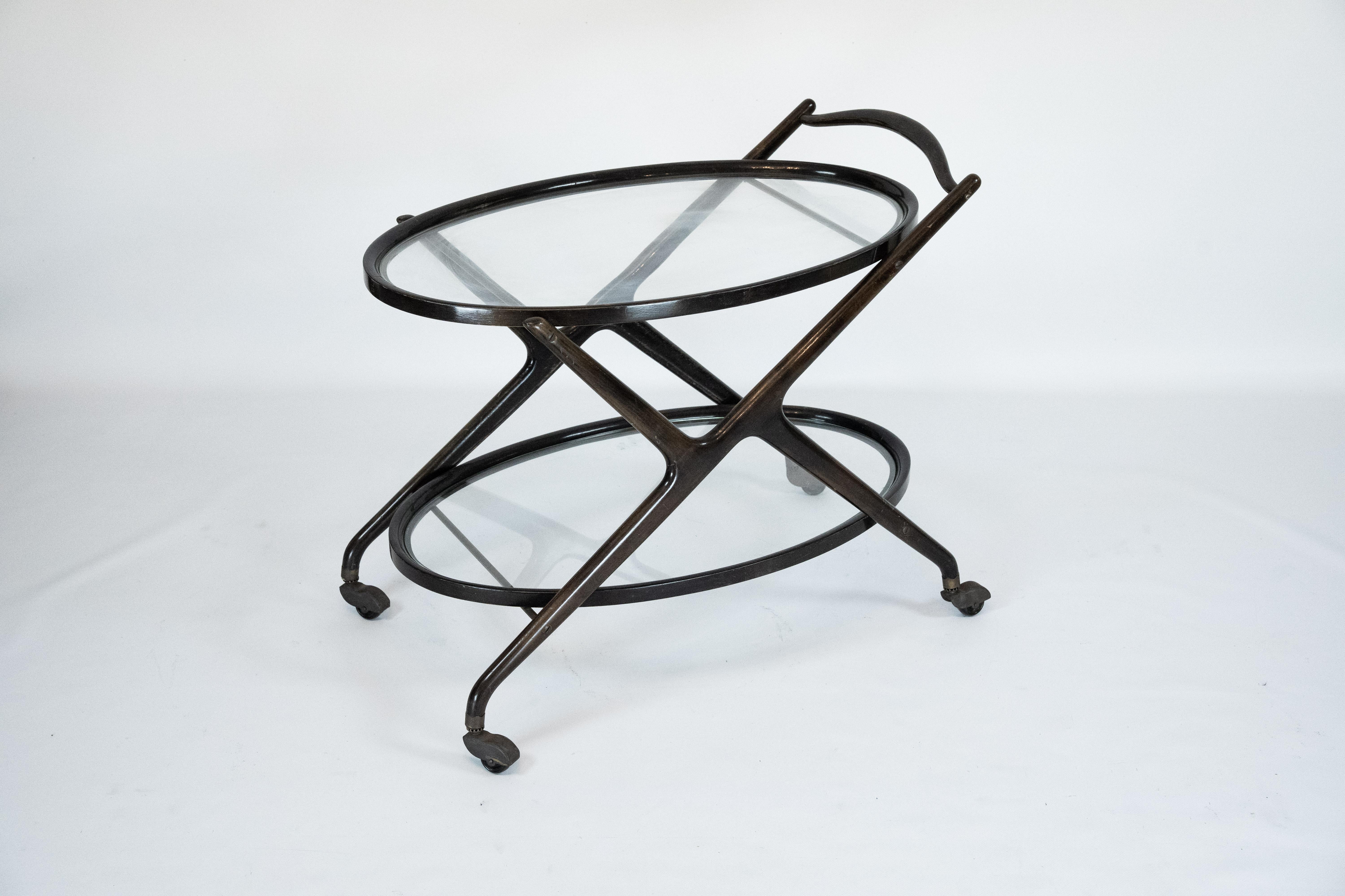 Elegant 1950s Italian bar cart by Cesare Lacca, crafted in ebonized wood with a refined sculptural structure and a circular glass top. The piece features Lacca’s characteristic flowing lines and balanced proportions, combining functionality with