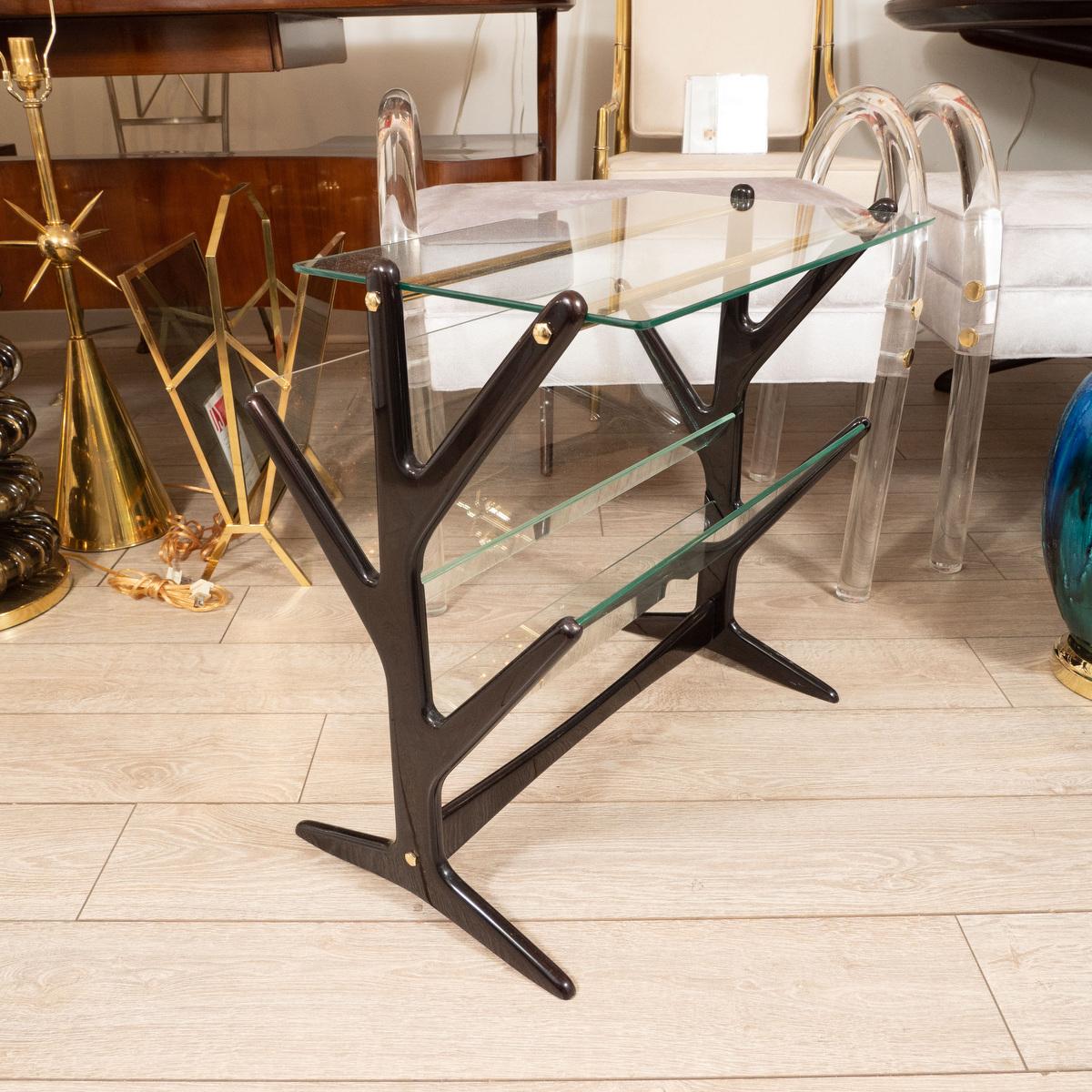 Angular, ebonized wood and glass side table with magazine holder and brass details.