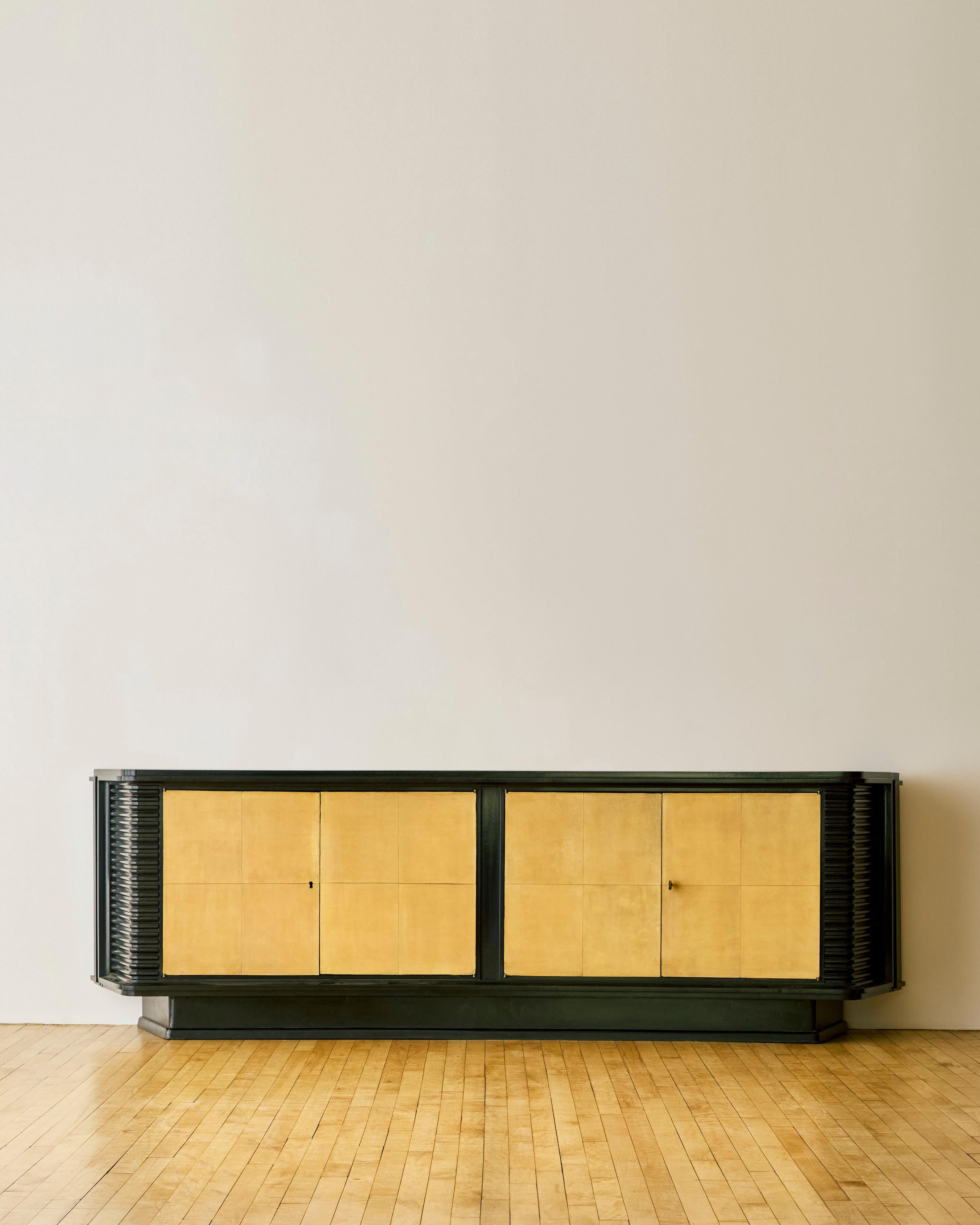 An ebonized wood and parchment deco sideboard with parchment covered doors on the interior. Exterior sides feature a ribbed design. Designed by Englander & Bonta c. 1940.