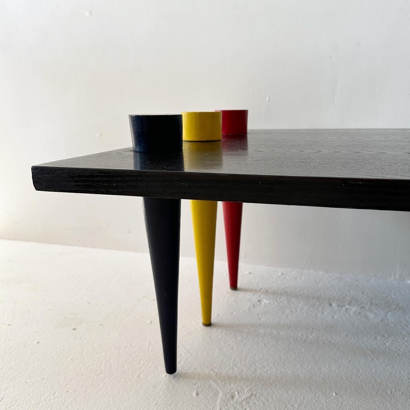 Ebonized wood waterfall coffee table with primary color conical legs. Kind of De Stilj energy.
​
L50 D28 H14 (table top - legs go up 2 more)