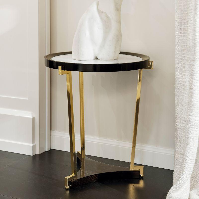 This gorgeous, minimalist, and modern side table features clean and sober lines that will make a timeless and versatile addition to any decor style. Resting on an ebony and brass base, it features a round glass top enriched with luminous silver
