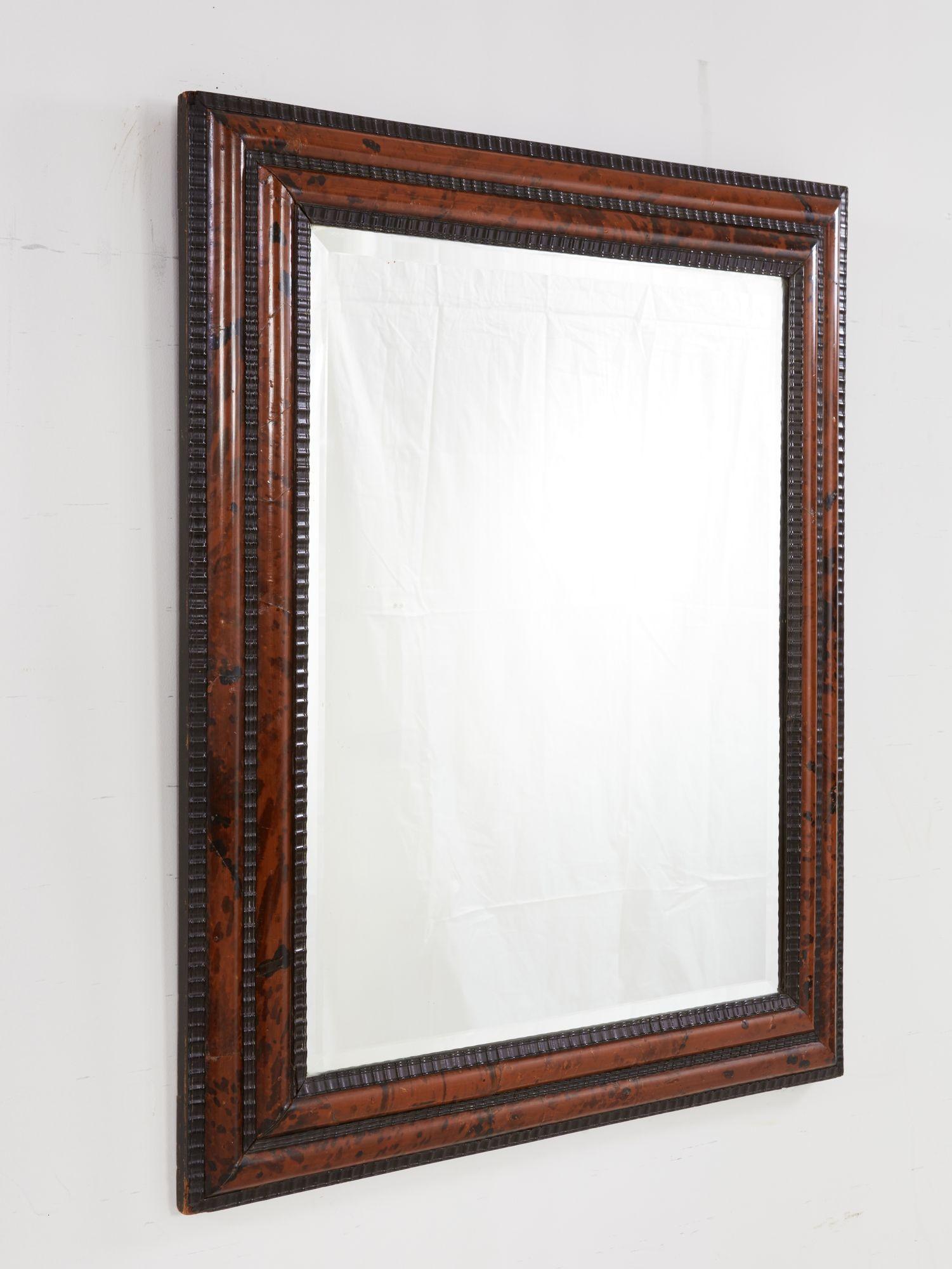 Good 19th century Flemish baroque faux tortoise and ebony mirror with original beveled plate, the two bands of red and black speckled shell flanked by three ripple carved ebony moldings.