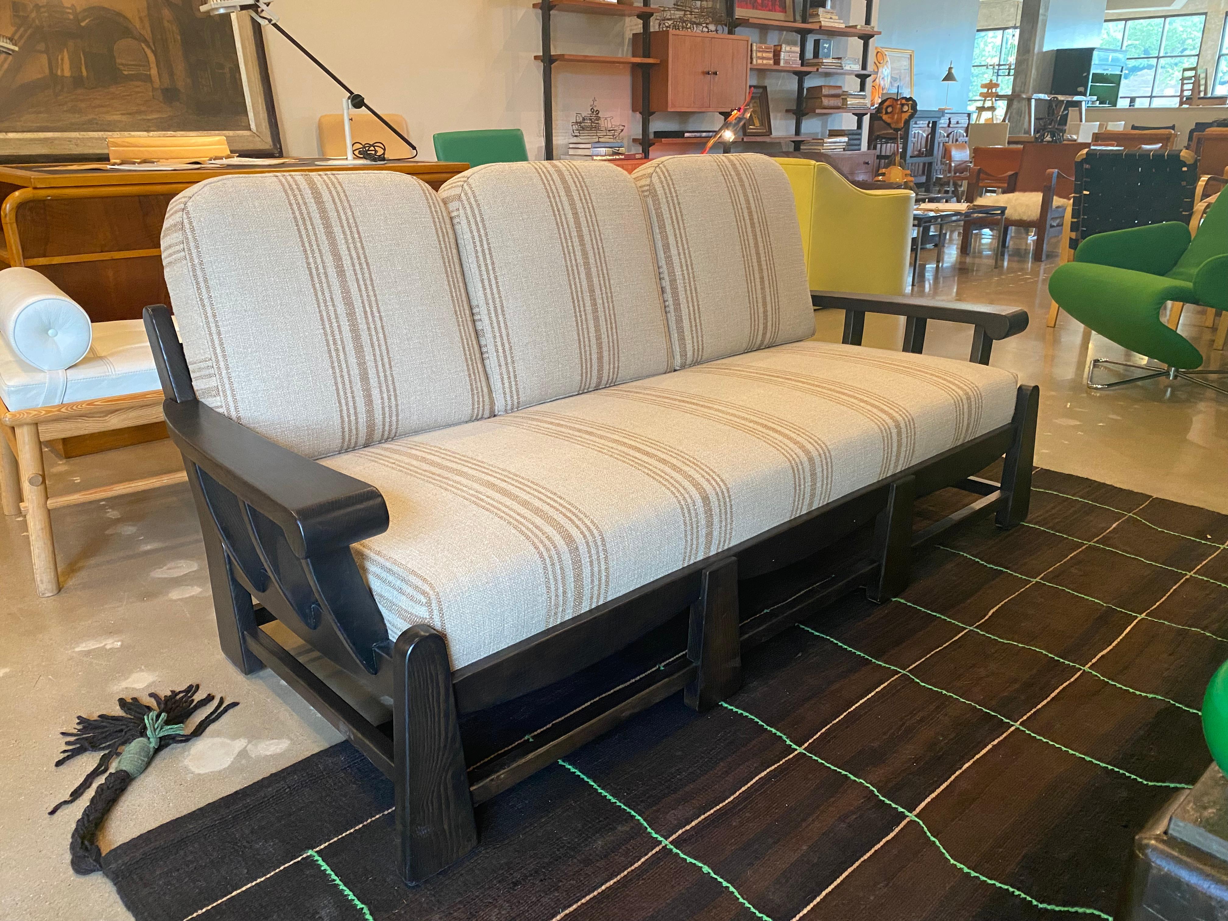 Sculptural ash (looks just like oak) sofa newly refinished in fine ebony stain by professional restorer. All new cushions and upholstery in striped Belgian linen. Comfortable and as good looking from the back as it is from the front in the distinct