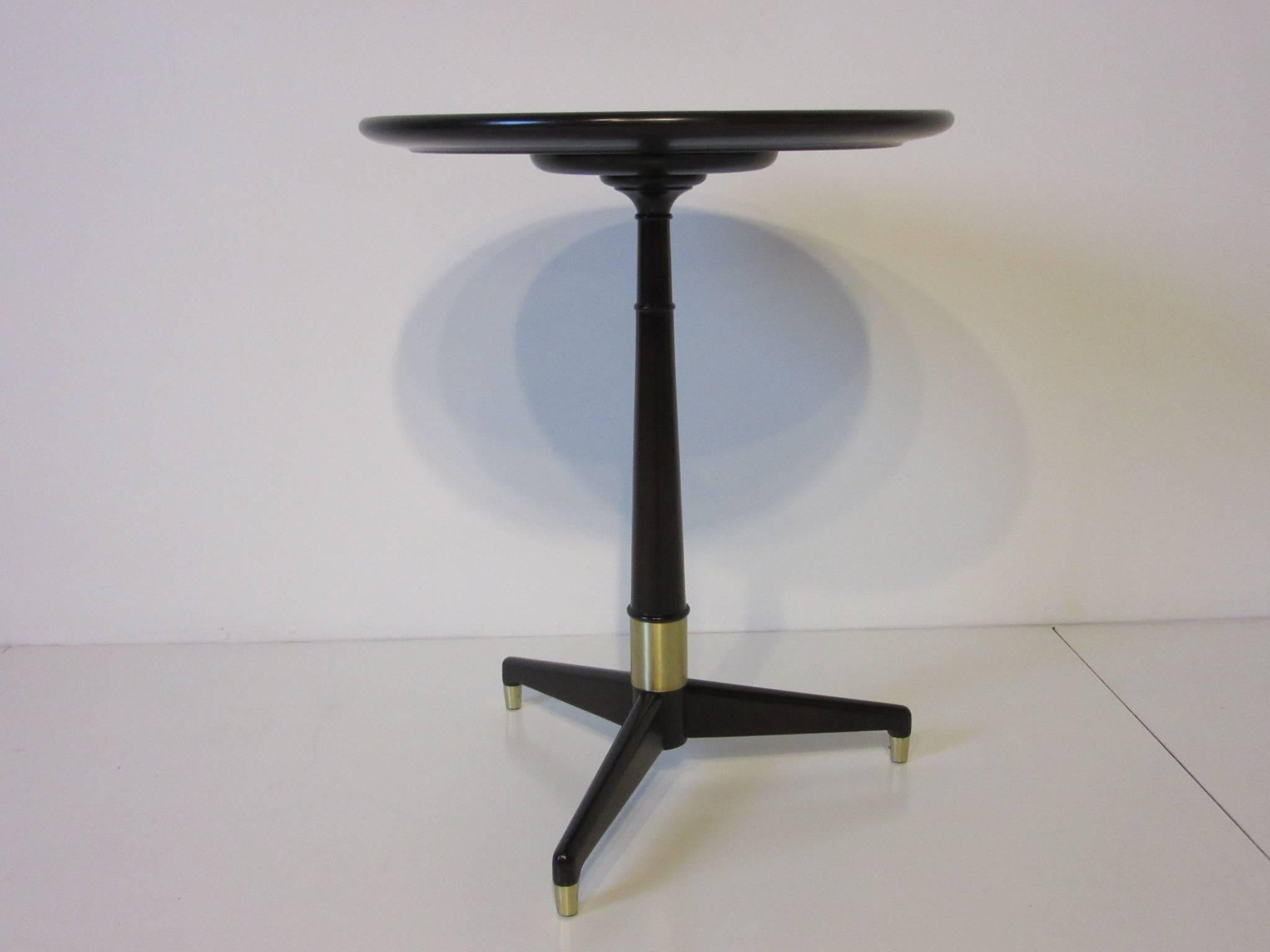 A dark and rich ebony finished side table with tri-pod base, brushed brass details and round top with raised lip. The perfect sized piece, simple and tailored for that special area, retains the manufactures tag to the underside W.M. Aberkey