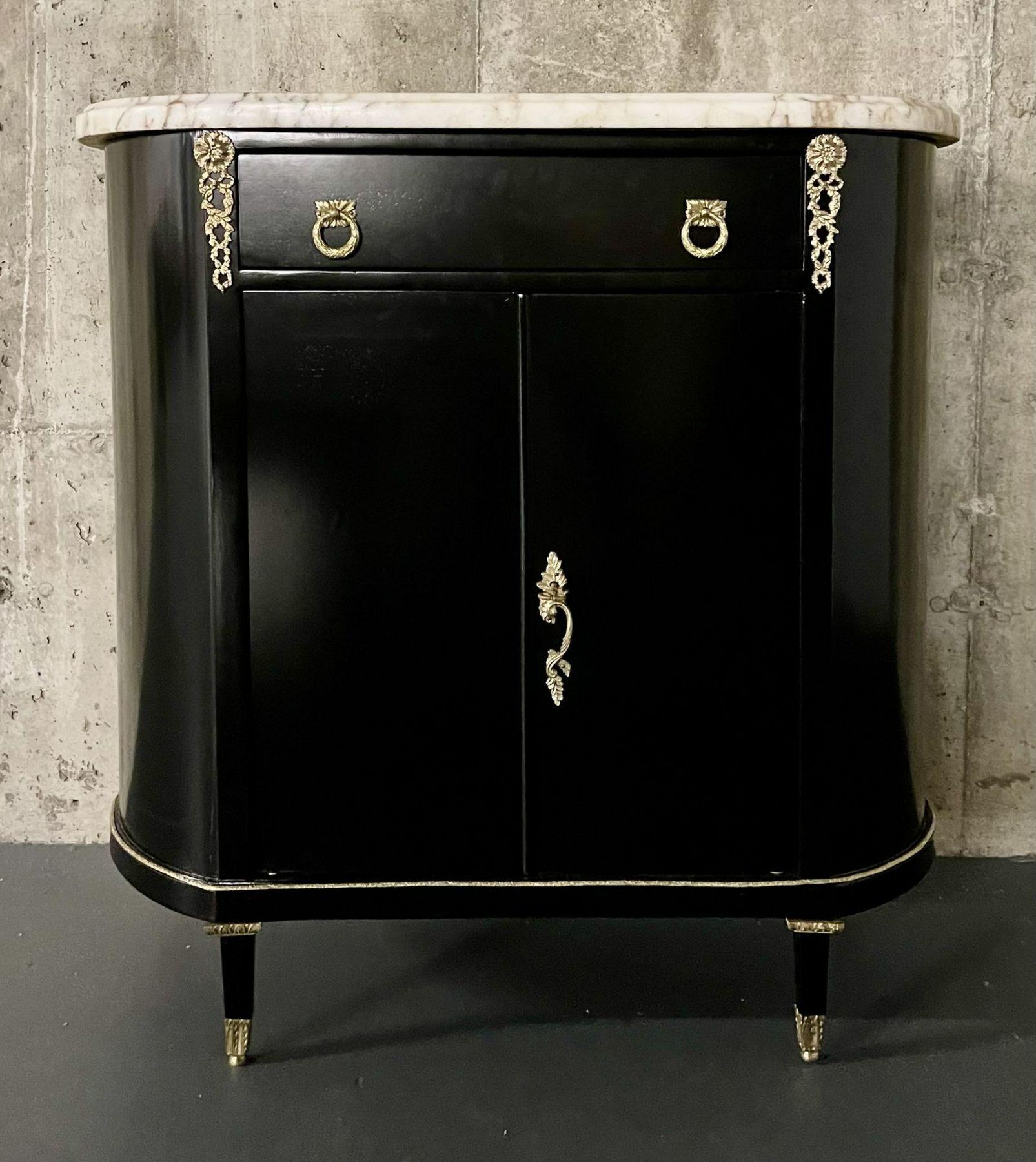 An early Hollywood Regency Style Demi Lune commode having bronze mounts and a marble top.
 
The two central doors leading to a fully finished ebony shelved interior flowing onto demi lune sides under a single drawer front allh having early dore