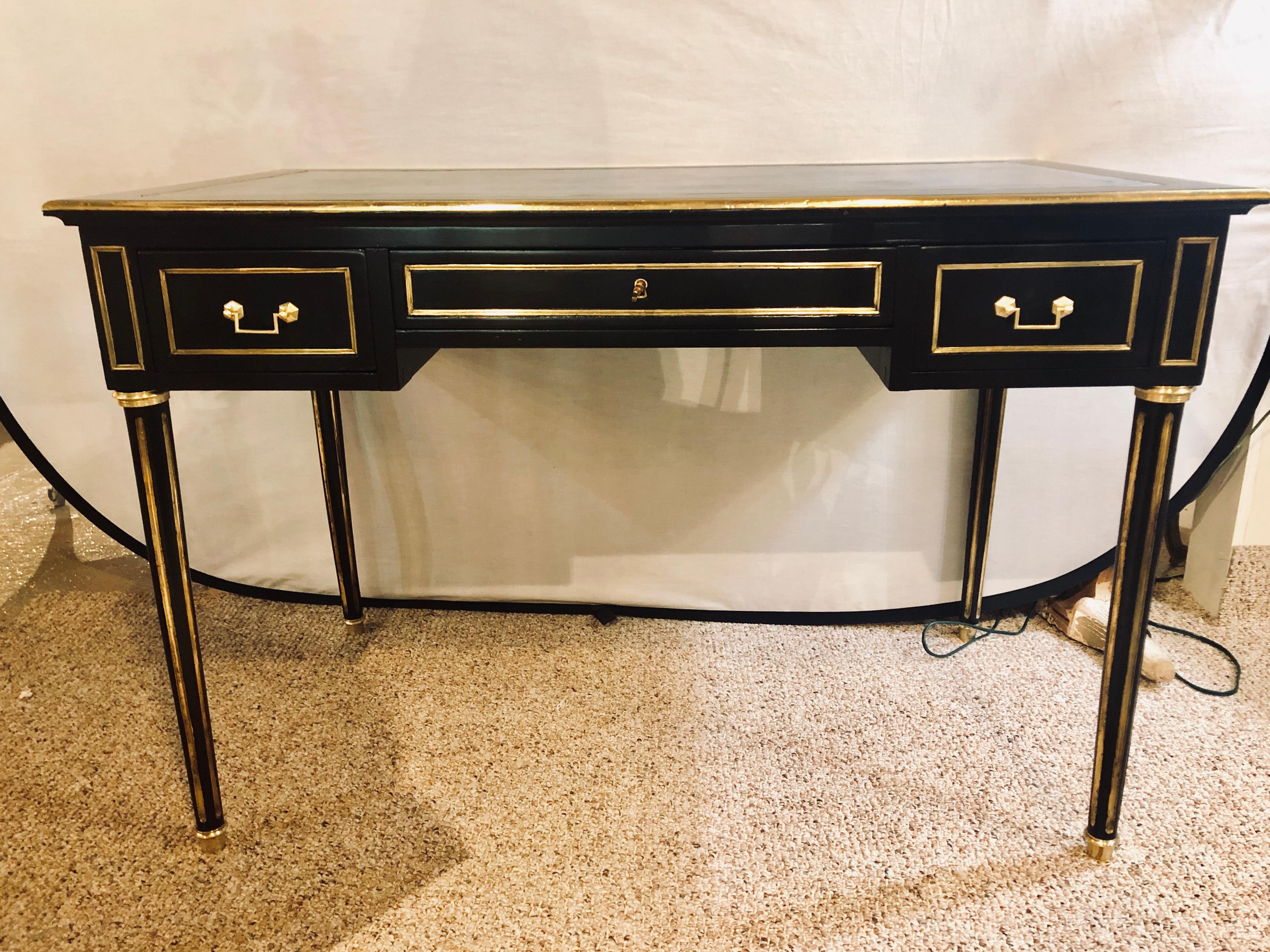 A Hollywood Regency bronze mounted writing table or office desk having a finely tooled leather top. This ebony Louis XVI Style writing table or desk is finely constructed the blueish and gilt gold tooled and worn leather top supported by a center
