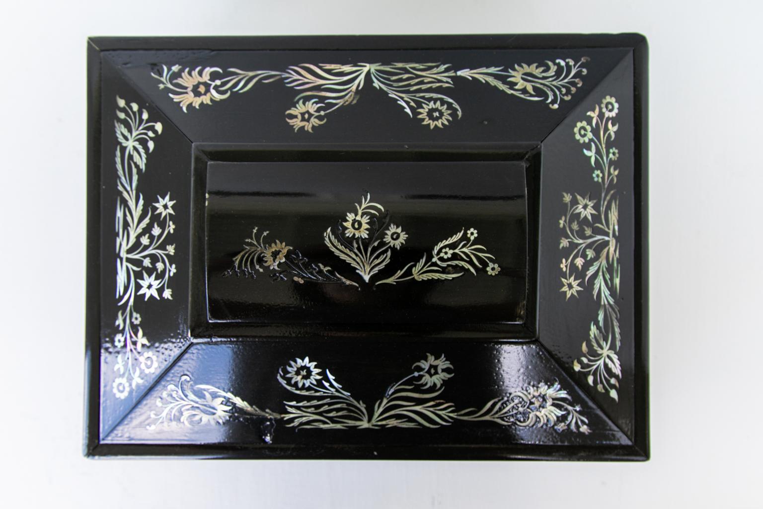 Ebony jewelry box, inlaid with mother of pearl floral arabesques. Cast brass lion head ring handles, it is resting on four reeded feet. There is some slight restoration, and some minor areas are missing mother of pearl.