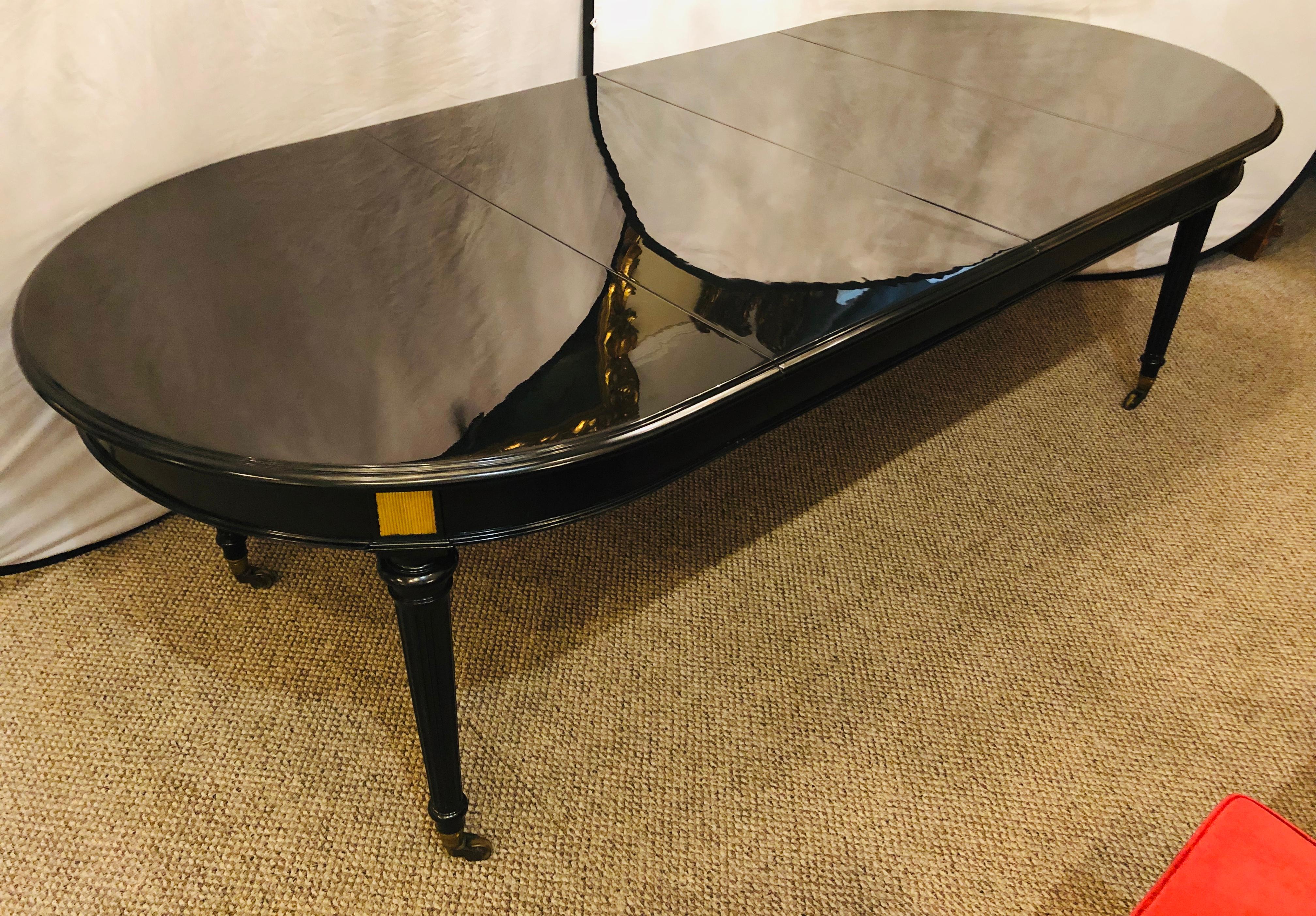 A very fine ebony lacquered Hollywood Regency Louis XVI style crank two leaf dining table in the manner of Maison Jansen. Having recently been given a Steinway Grand black finish this wonderful Double 21 inch leaf dining table is certain to shine in