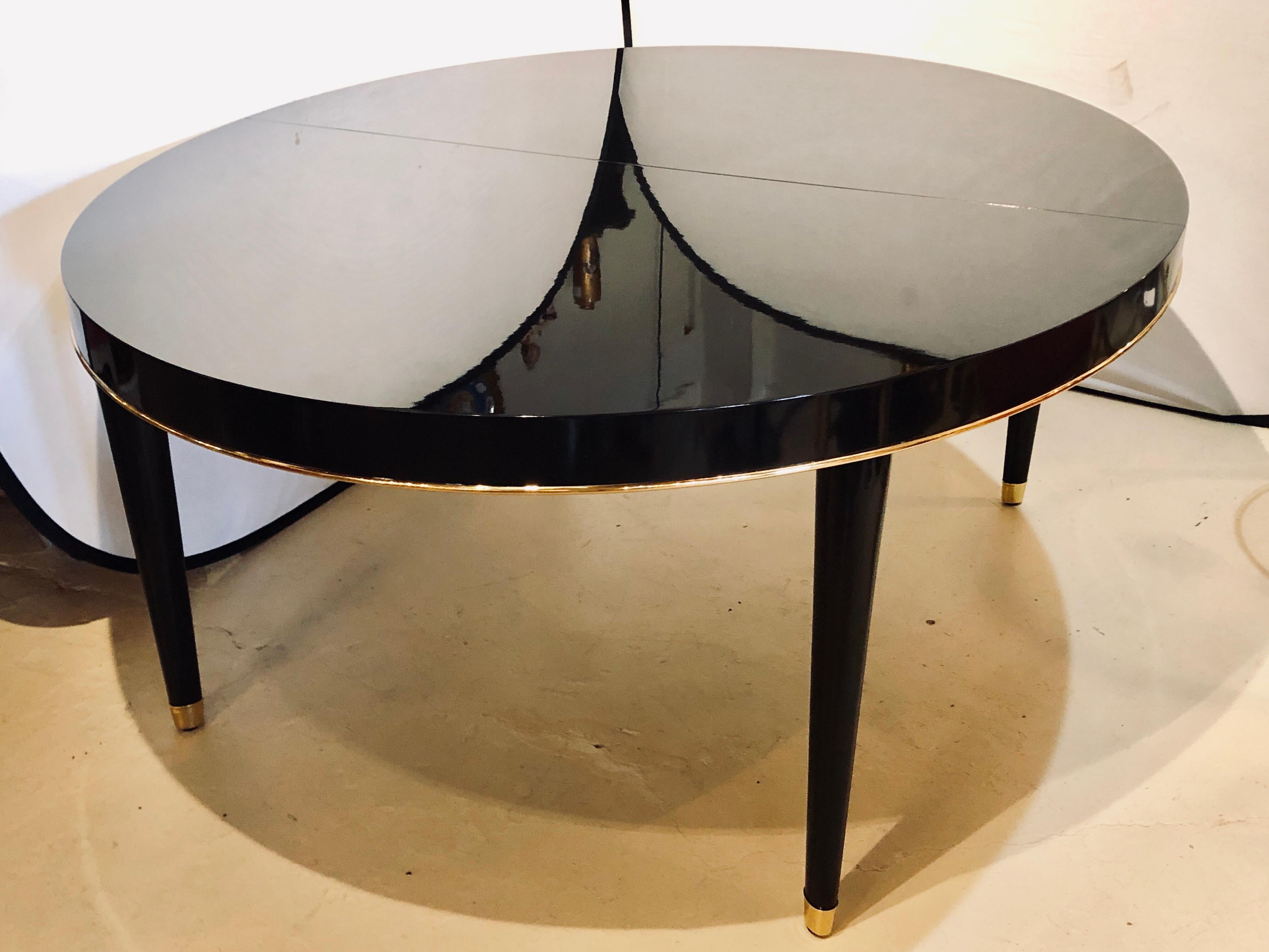 Ralph Lauren Paris one fifth dining room table with one leaf measuring 24 inches. this fully refinished dining table has an ebony lacquered finish the likes of the finest Steinway piano w outstanding gilt metal trim and sabots. The sleek and stylish