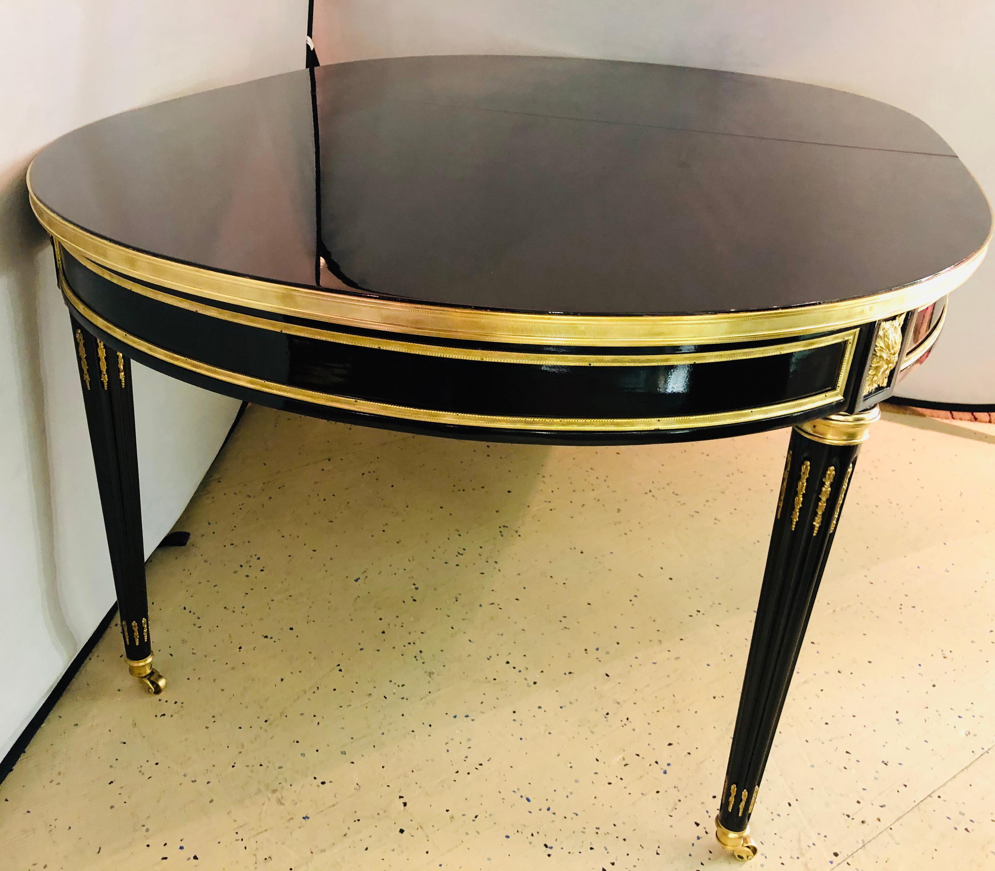 A Maison Jansen 1940s dining table Numbered 172A in several places. Louis XVI style having fine bronze mounts and a spectacular tabletop finish. This stunning Steinway Piano finished tabletop sits with two small and one large leaf. The tabletop