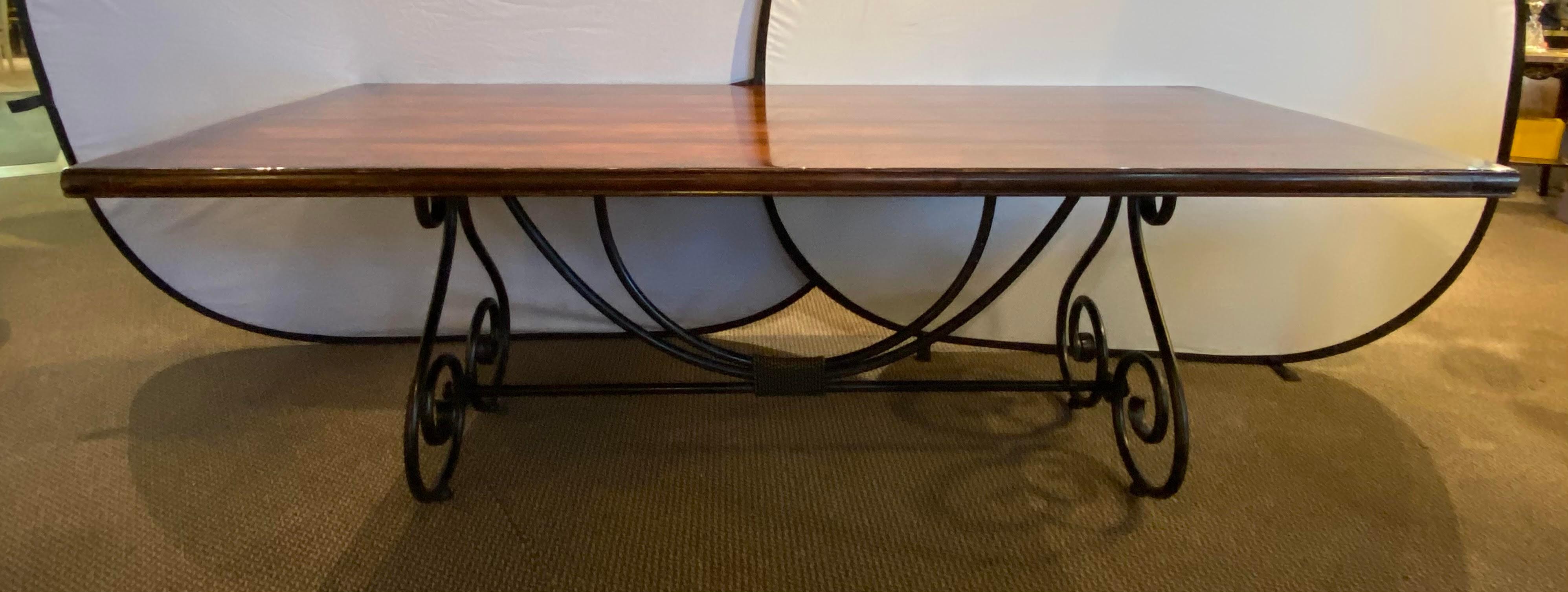 Table de salle à manger à base de volutes en métal et laiton finement travaillées. Le plateau en bois est soutenu par une base de style baroque en fer avec des décorations en fil de laiton. Une table de salle à manger ou de conférence
