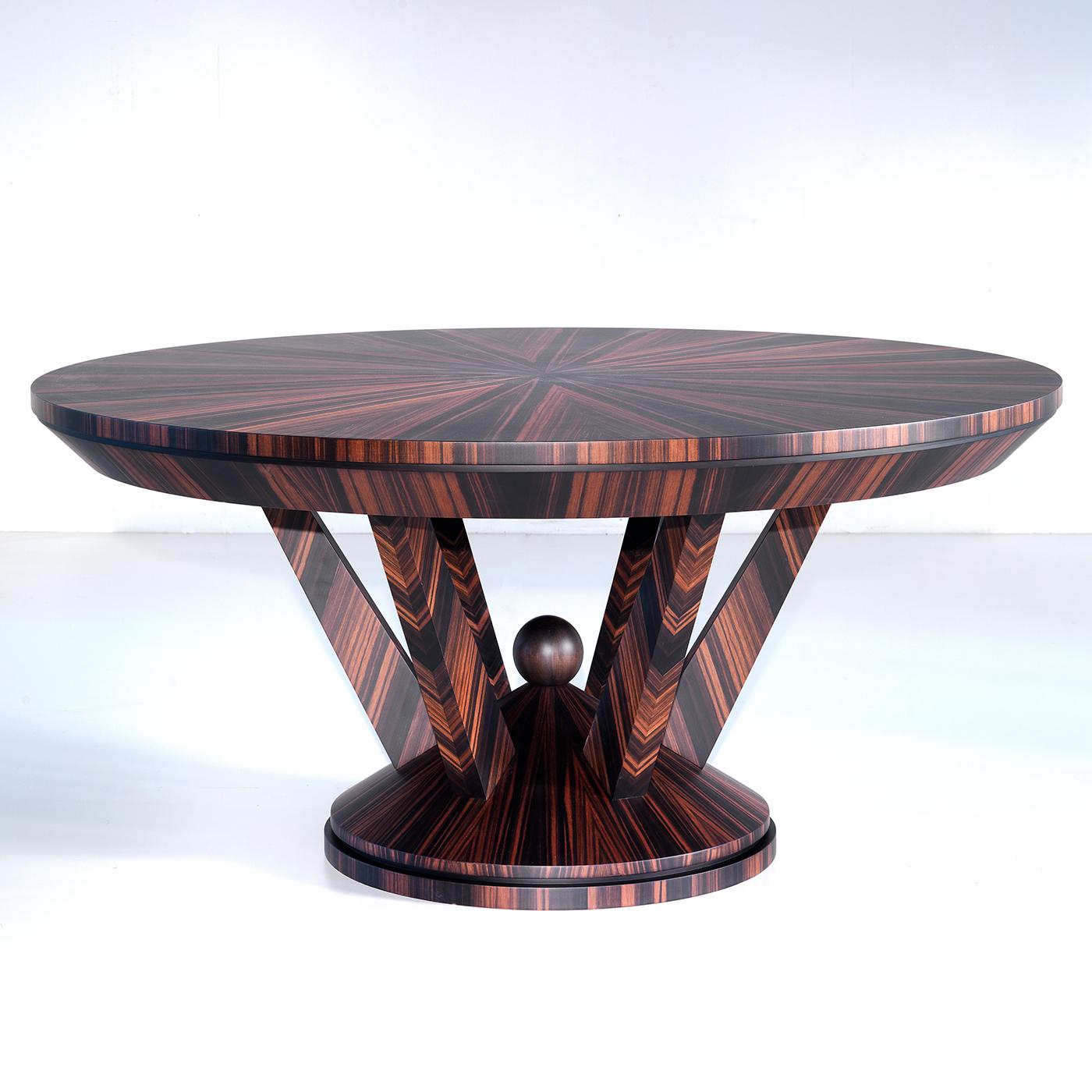 The eye-catching, geometric patterns identifying the natural beauty of Makassar ebony is the hallmark of this imposing round dining table. Four bold, slanted elements rise from a conical base enlivened by a spherical finial to efficiently sustain
