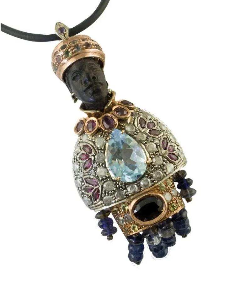 Vintage Moretto Pendant realized with finely carved ebony face, 9k rose gold and silver chest enriched with diamonds, rubies, blue sapphires and a central aquamarine. The rose gold hat is enriched by tourmaline and tsavorite
The origin of this