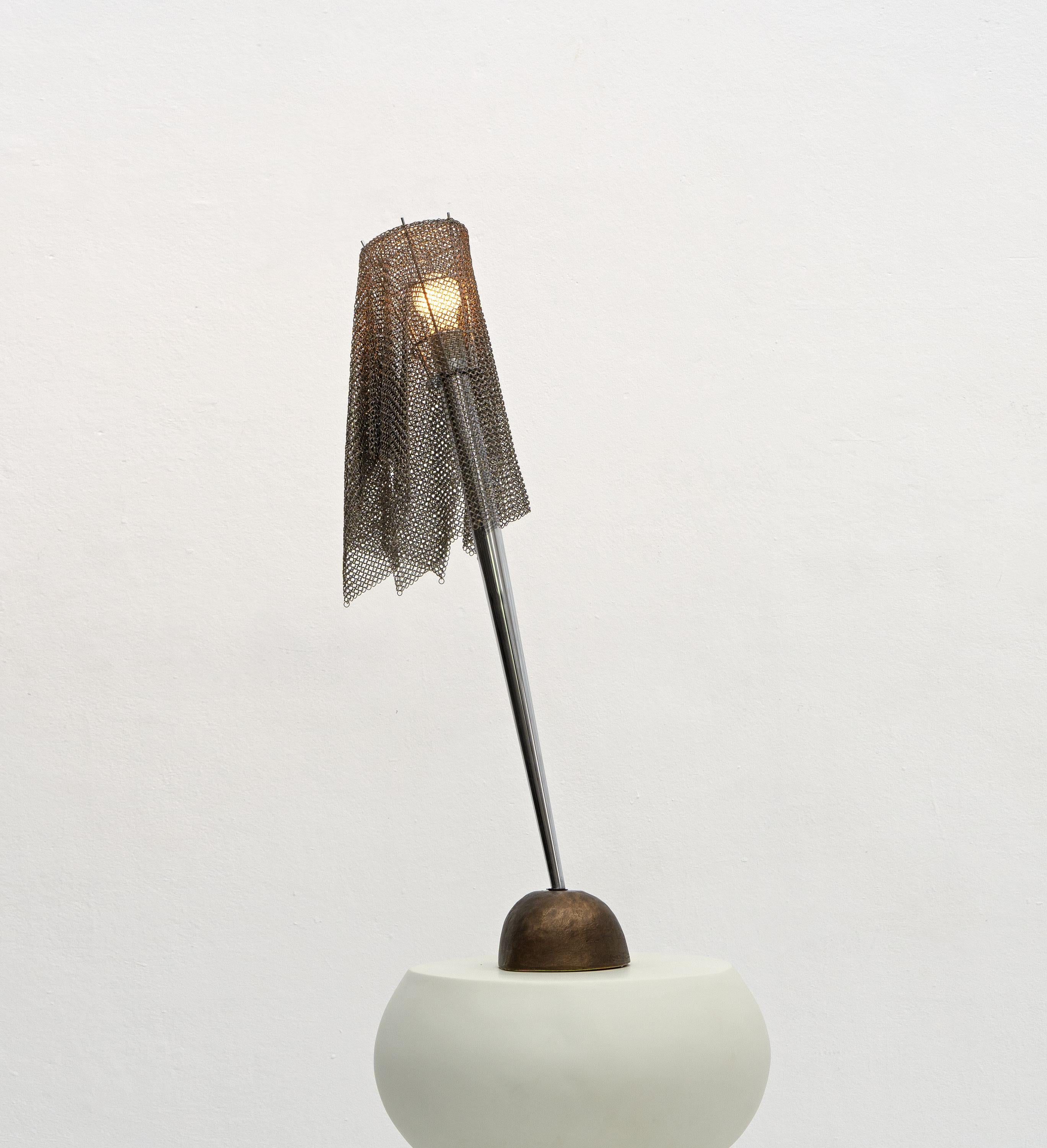 A Postmodern 'Ecate' table lamp designed by Toni Cordero and produced by Italian lighting behemoth Artemide in the 1990's. 

A great example of postmodern design featuring a chrome conical stem protruding from a brass rock-like base to support a