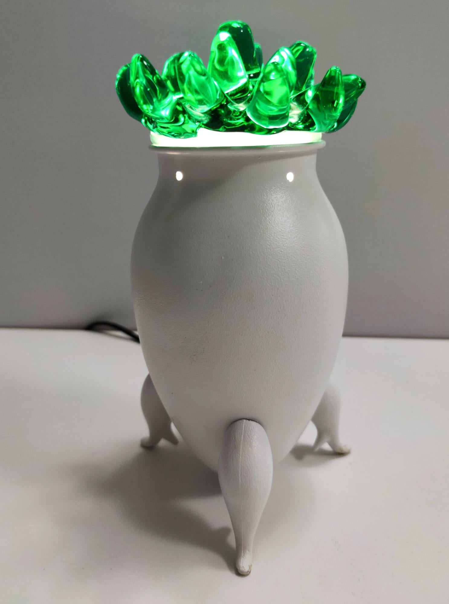 Fabriqué en Italie, années 1980. 
Cette lampe de table excentrique est fabriquée en verre de Murano et en aluminium verni blanc. 
Il ressemble à une plante en pot ou à une créature particulière. 

Il s'agit d'une pièce d'époque, qui peut donc