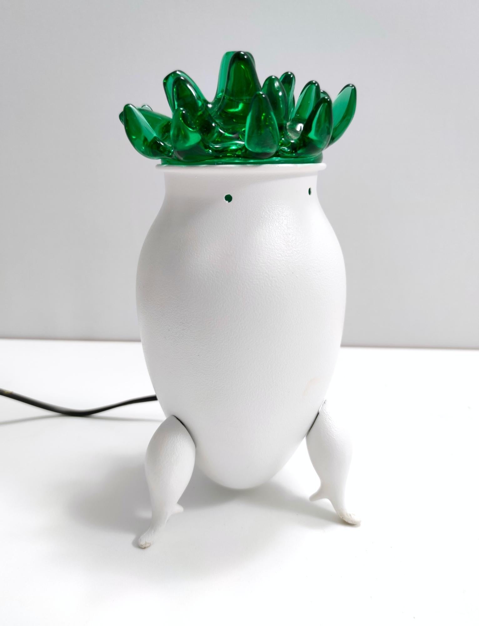 Fabriqué en Italie, années 1980. 
Cette lampe de table excentrique est fabriquée en verre de Murano et en aluminium verni blanc. 
Il ressemble à une plante en pot ou à une créature particulière. 

Il s'agit d'une pièce d'époque, qui peut donc