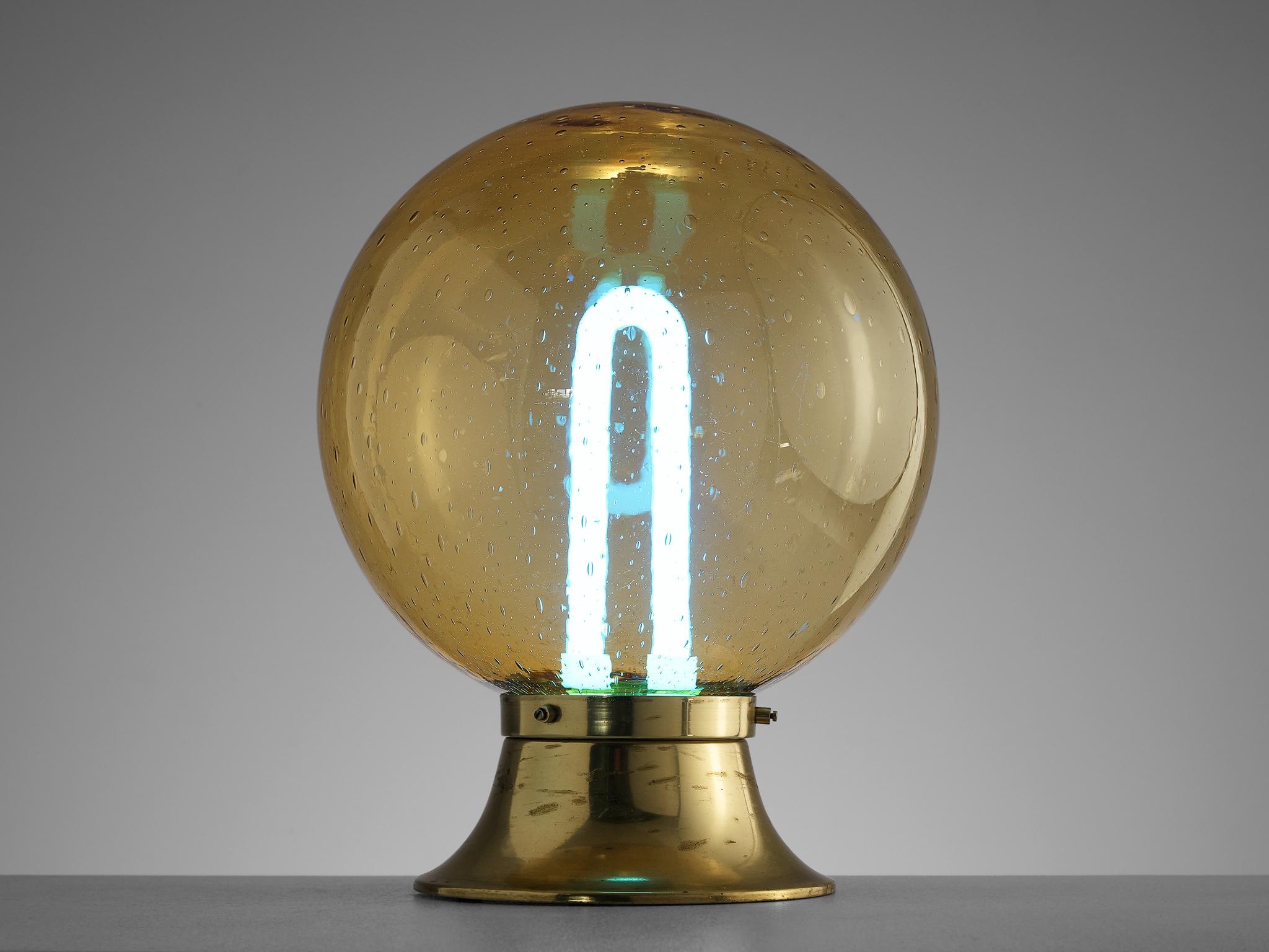 Table lamp, brass, glass, Europe, 1960s 

This stunning desk lamp features an exquisite glass sphere showing a nice structure of little bubbles or raindrops. This results in a nice and soft light-tone creating an atmospheric light partition. The