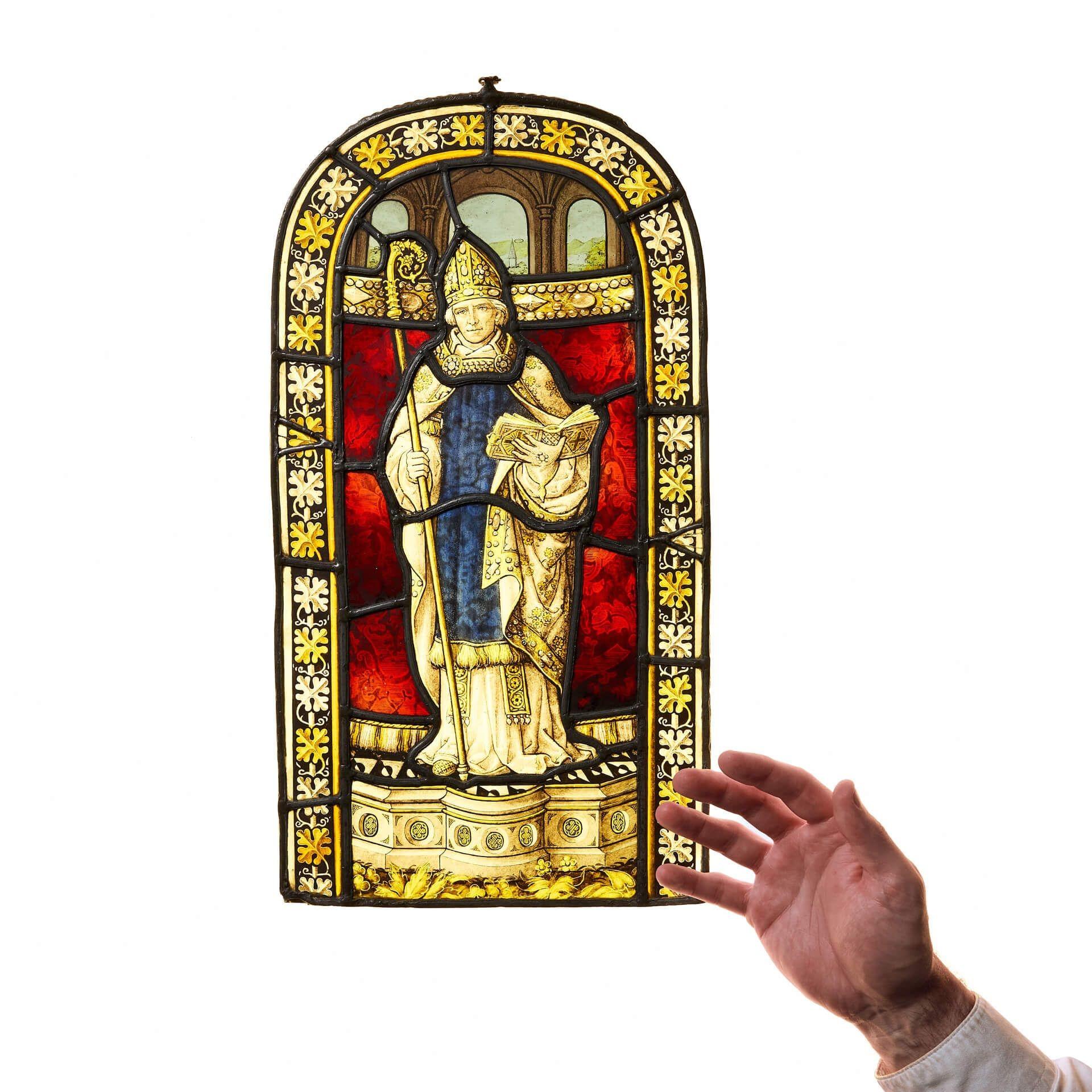 Antigua vidriera eclesiástica que representa a un obispo, hacia 1890. Diseñado con una distintiva forma arqueada, este panel de vidriera se asemeja a una pequeña ventana de iglesia.

El obispo va vestido de azul, con una larga capa llamada capa