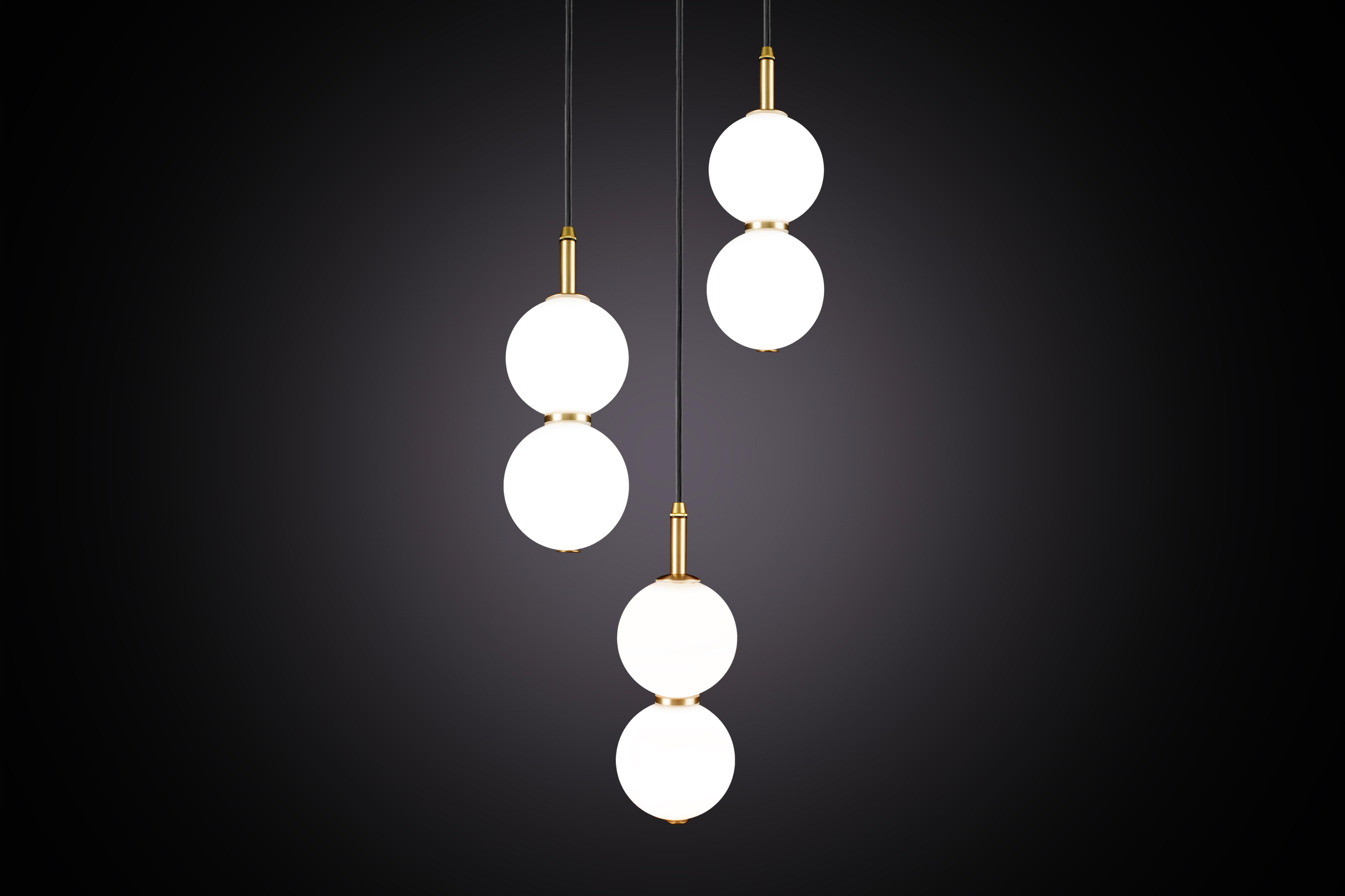 Deux délicats orbes en verre opalin blanc empilés l'un sur l'autre pour créer un éclat de lumière en écho et l'illusion de reflets subtils.