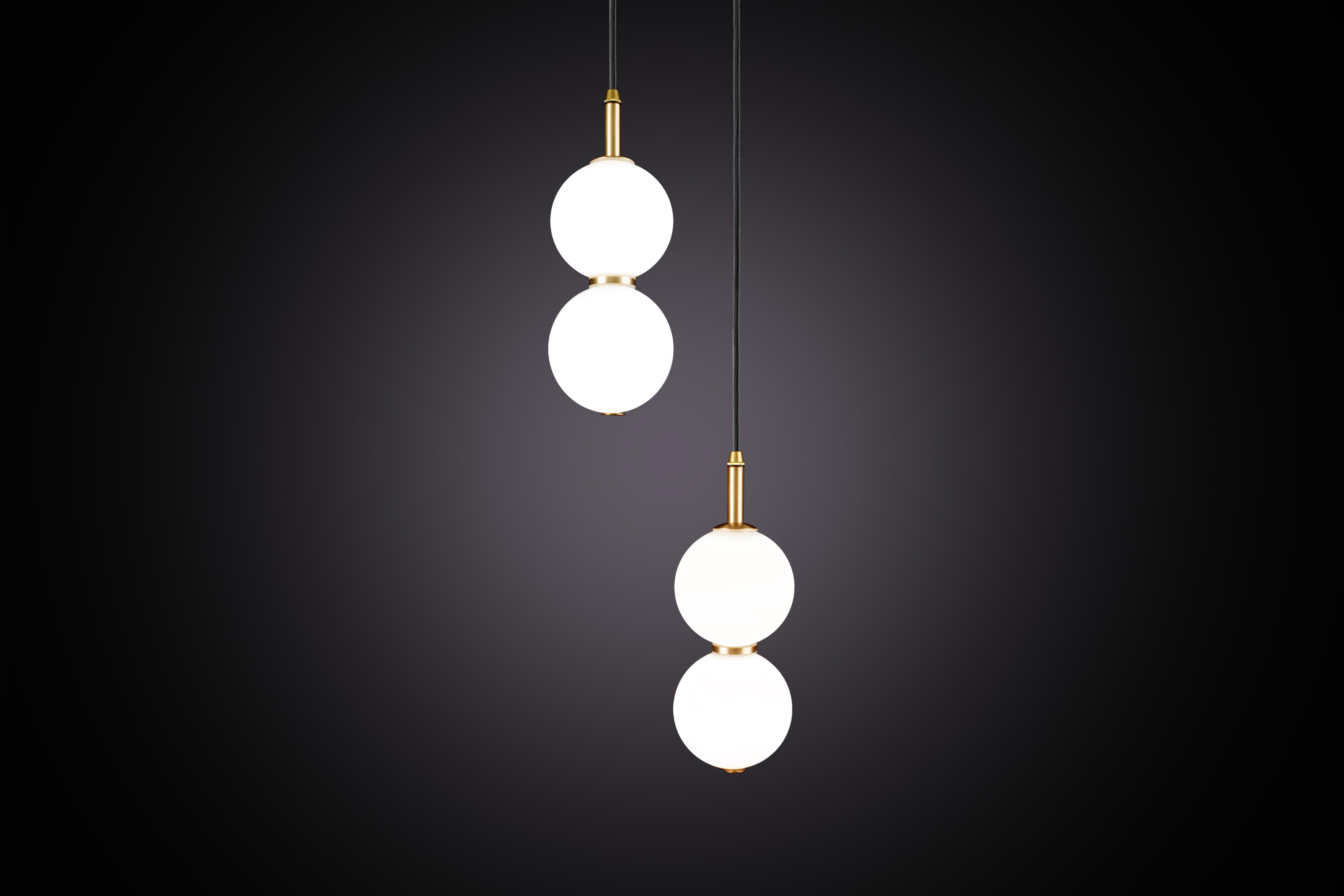 Due delicate sfere di vetro opalino bianco impilate l'una sull'altra per creare un'eco di luce e l'illusione di sottili riflessi.