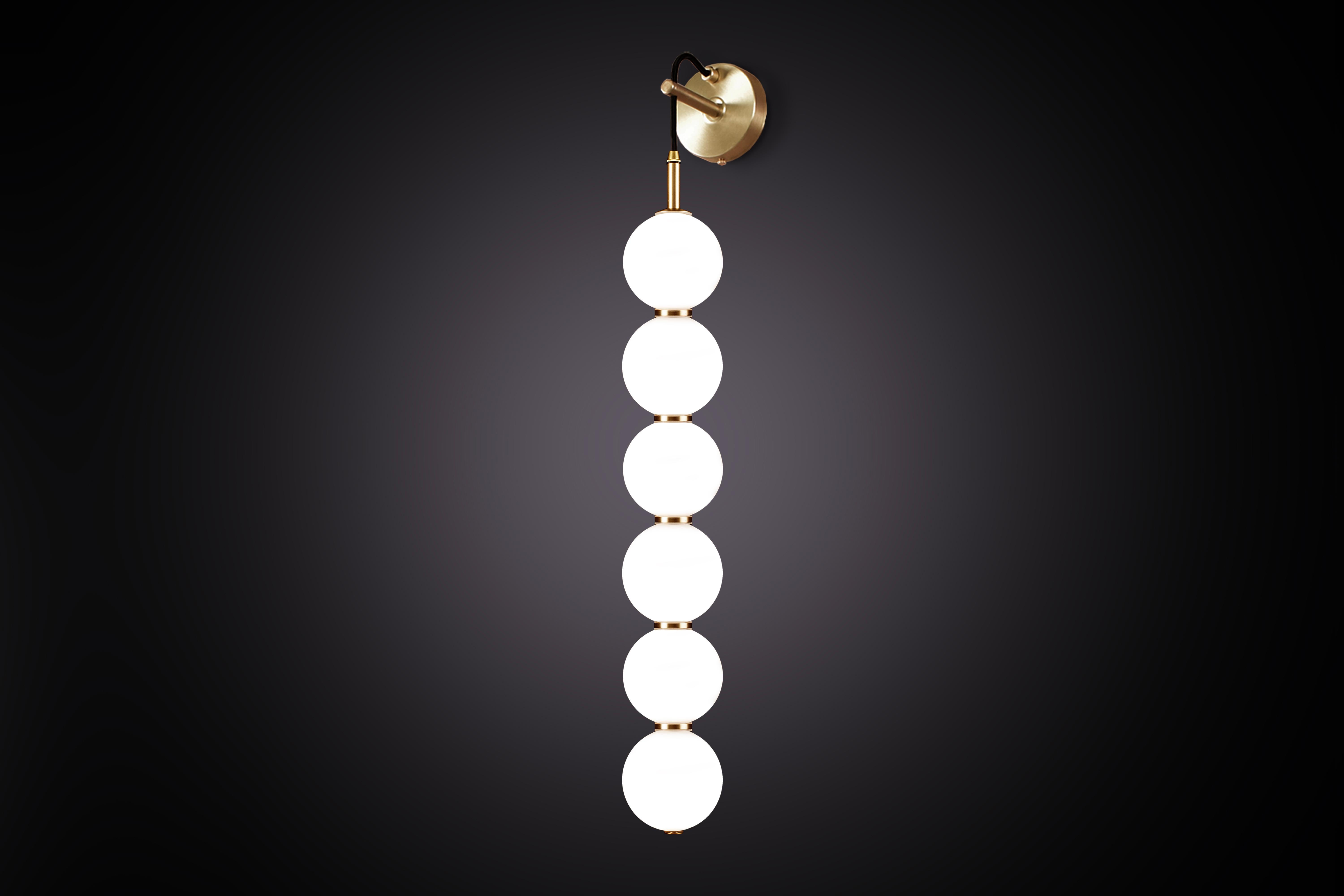 De délicats orbes de verre opalin blanc empilés les uns sur les autres pour créer une lueur de lumière en écho et l'illusion de subtils reflets.