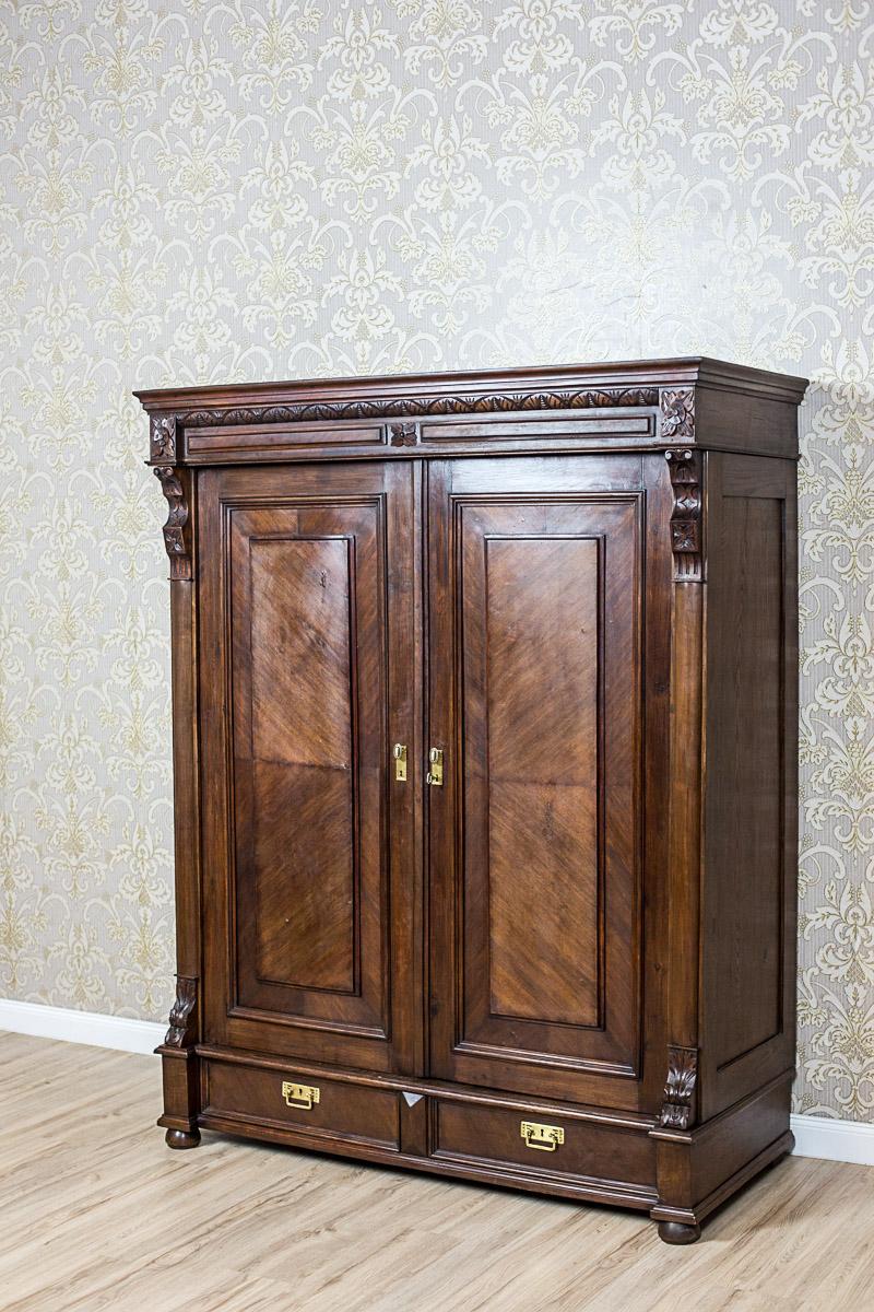 The closet is two-door, with an advanced cornice with two drawers.
The upper section ends with a simple crest. The crest is decorated with a stripe with an ornament, and a profiled crown molding.
The doors are flanked by pilasters.
Furthermore,